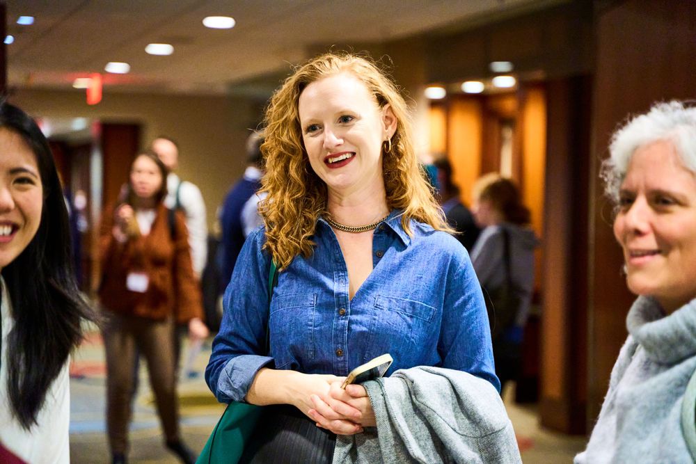 Three people engaging in conversation at a conference or social gathering.