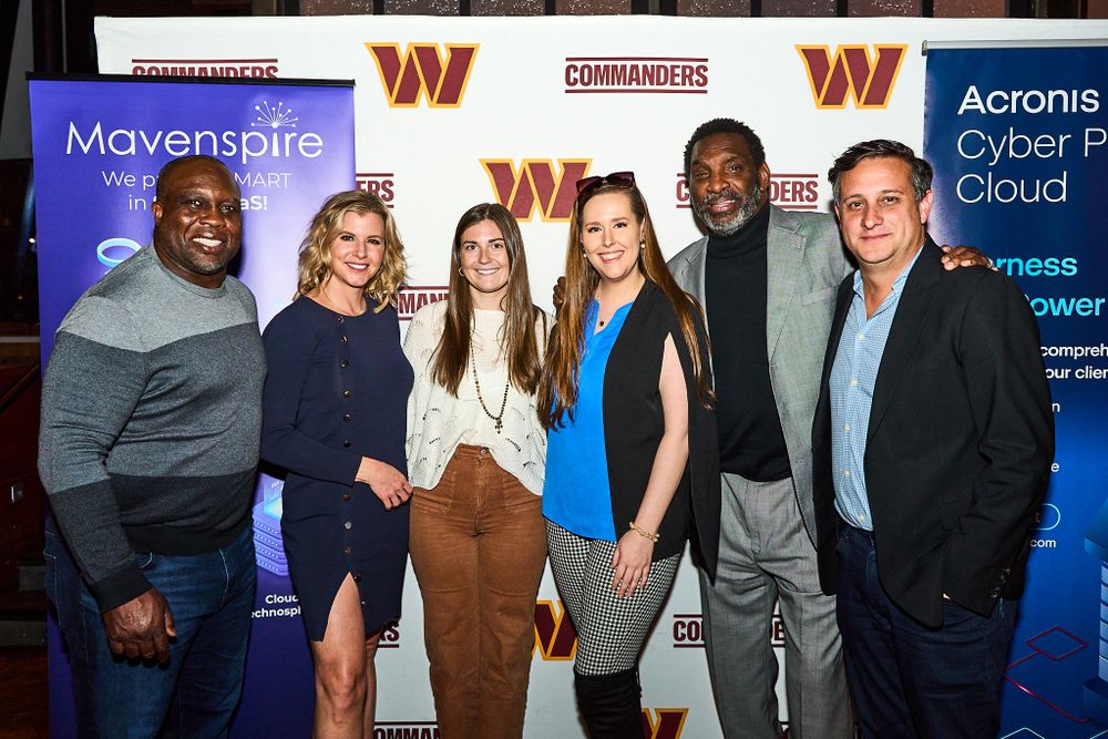Group photo of diverse professionals at a corporate Mavenspire technology event with branded backdrop.