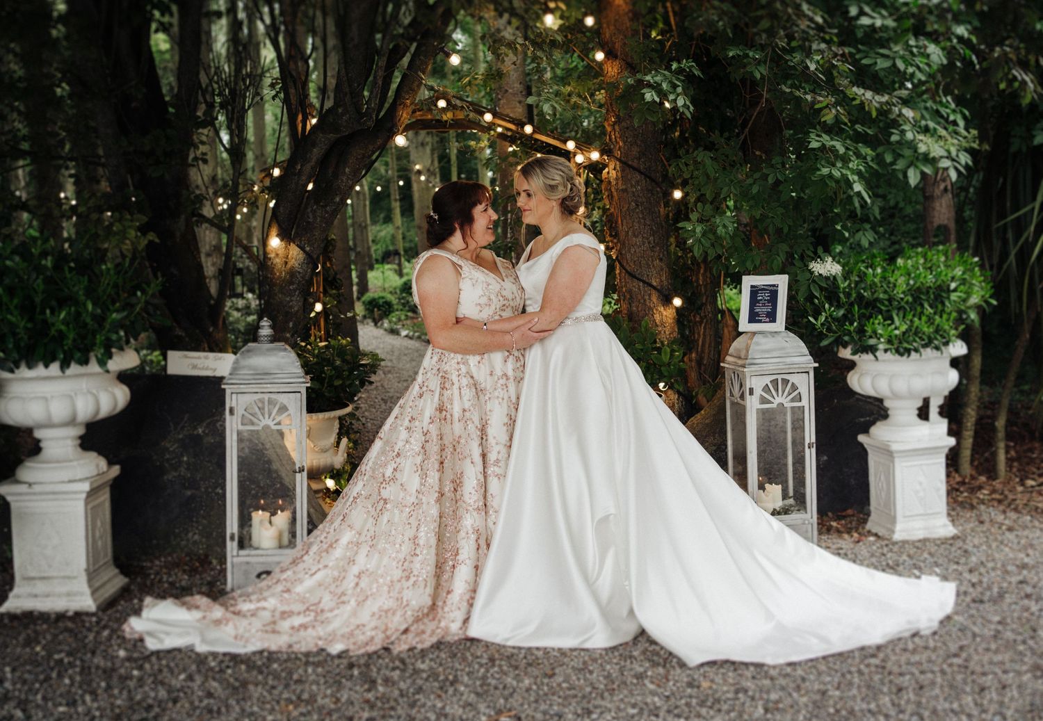Wedding ceremony setup with string lights and lanterns in a romantic outdoor garden setting.