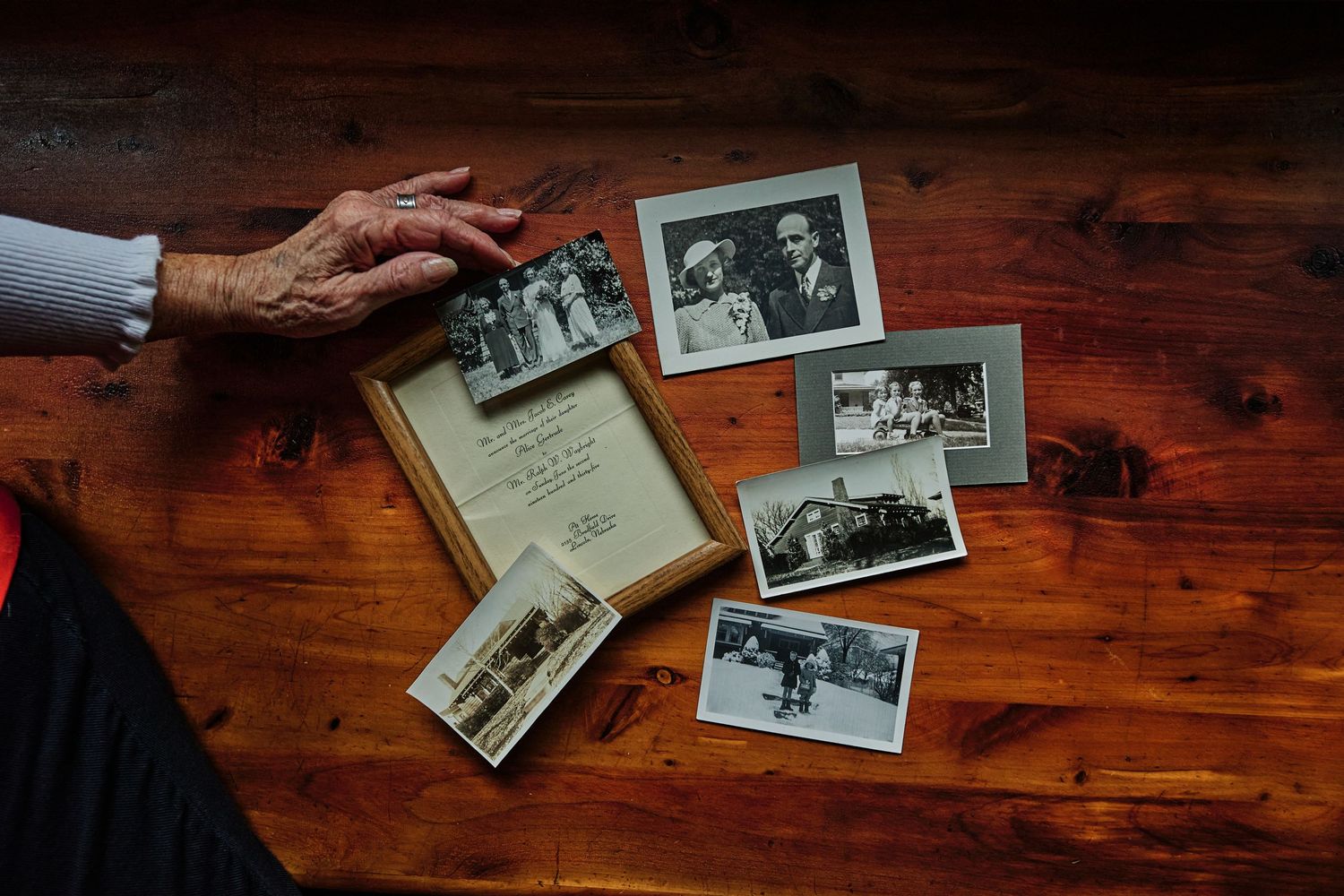 Old black and white photographs spread out on a wooden table surface.