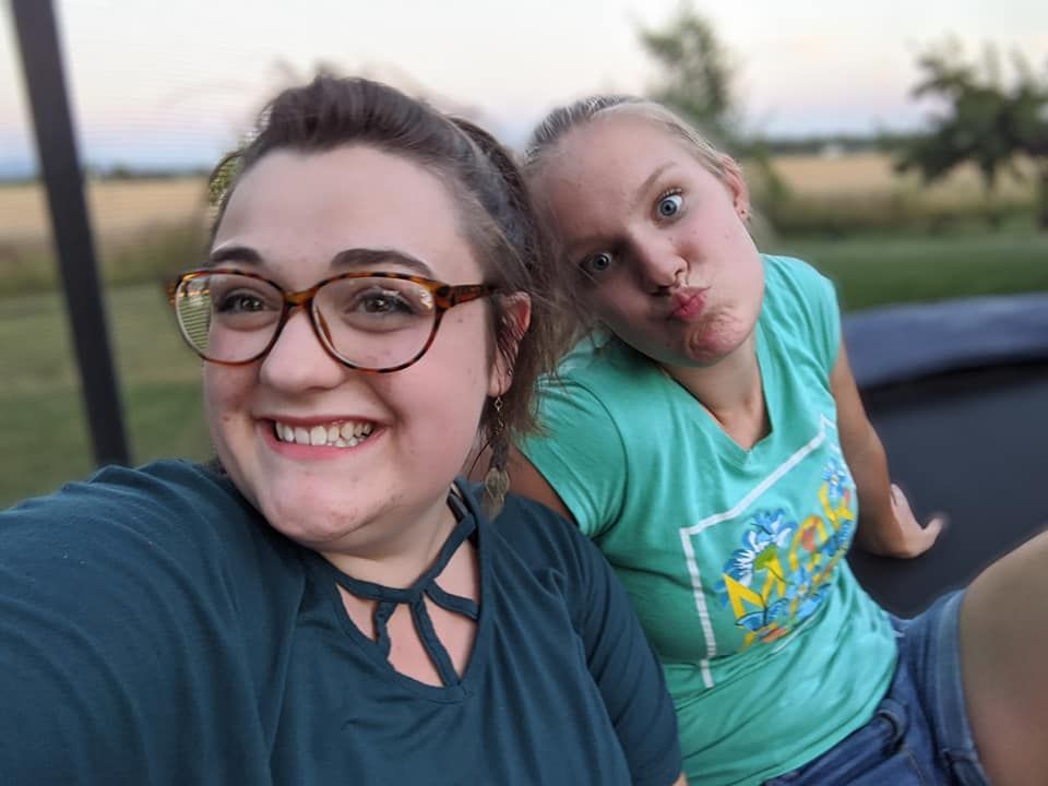 Two people take a selfie together outdoors during sunset.