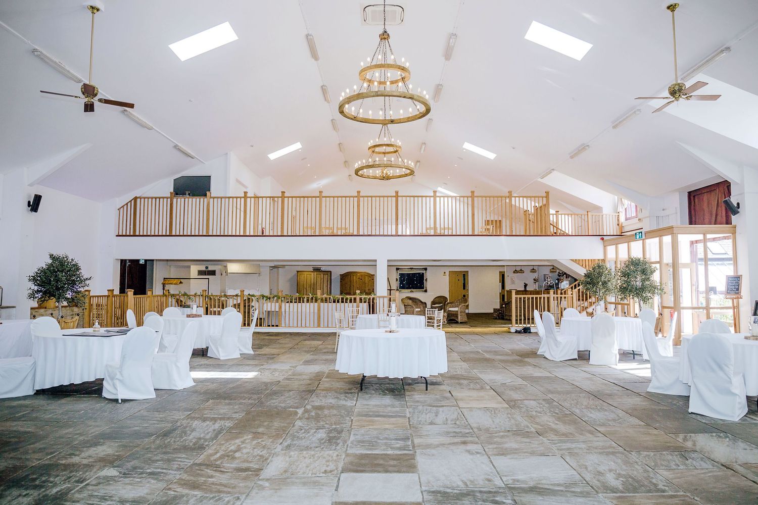 Large white reception hall with vaulted ceilings, chandeliers, and a mezzanine level.
