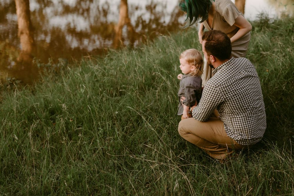 Family enjoying a tender moment together in a sunlit grassy field at golden hour.