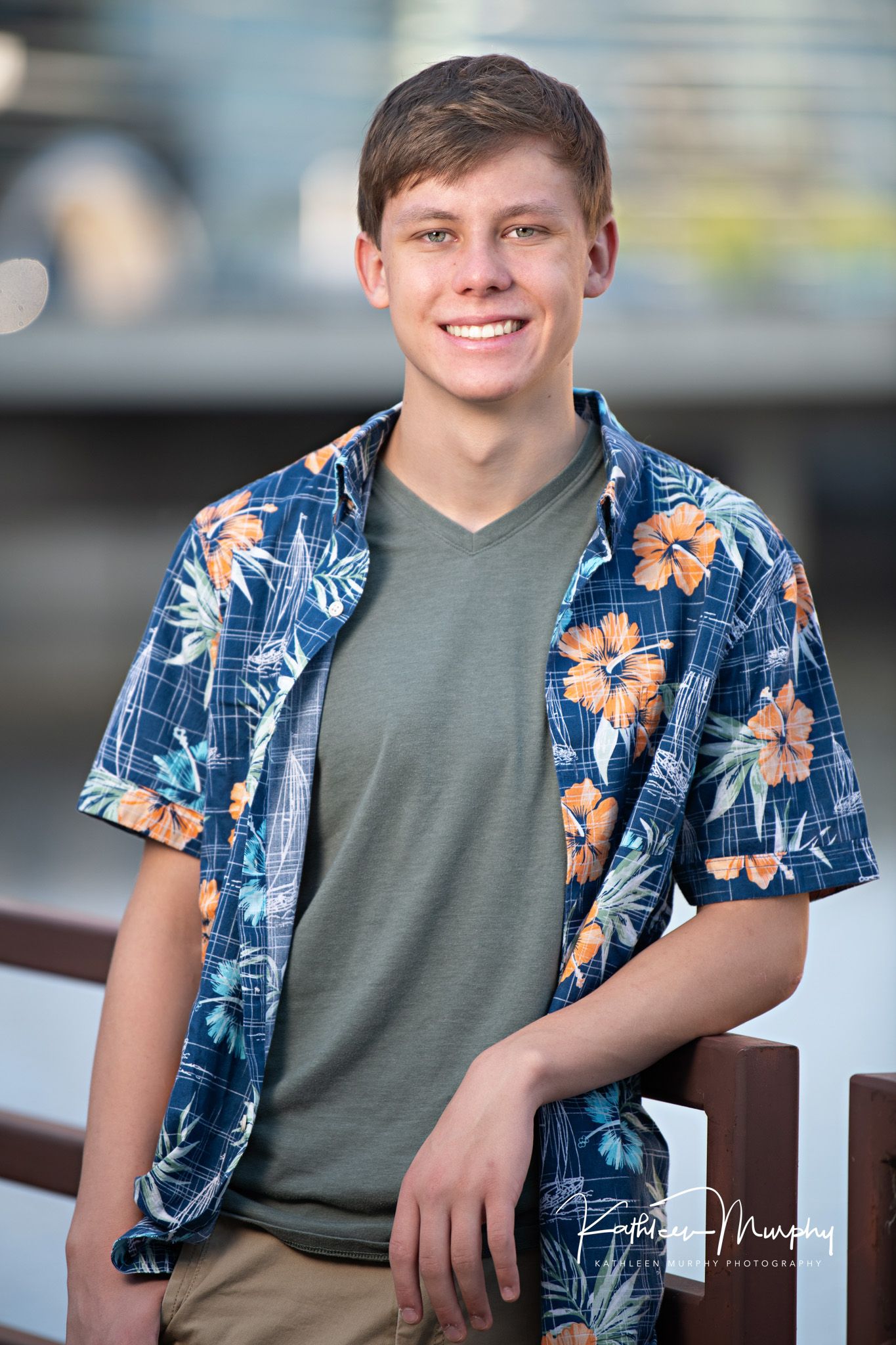 Portrait of person wearing floral Hawaiian shirt and olive t-shirt against blurred background.
