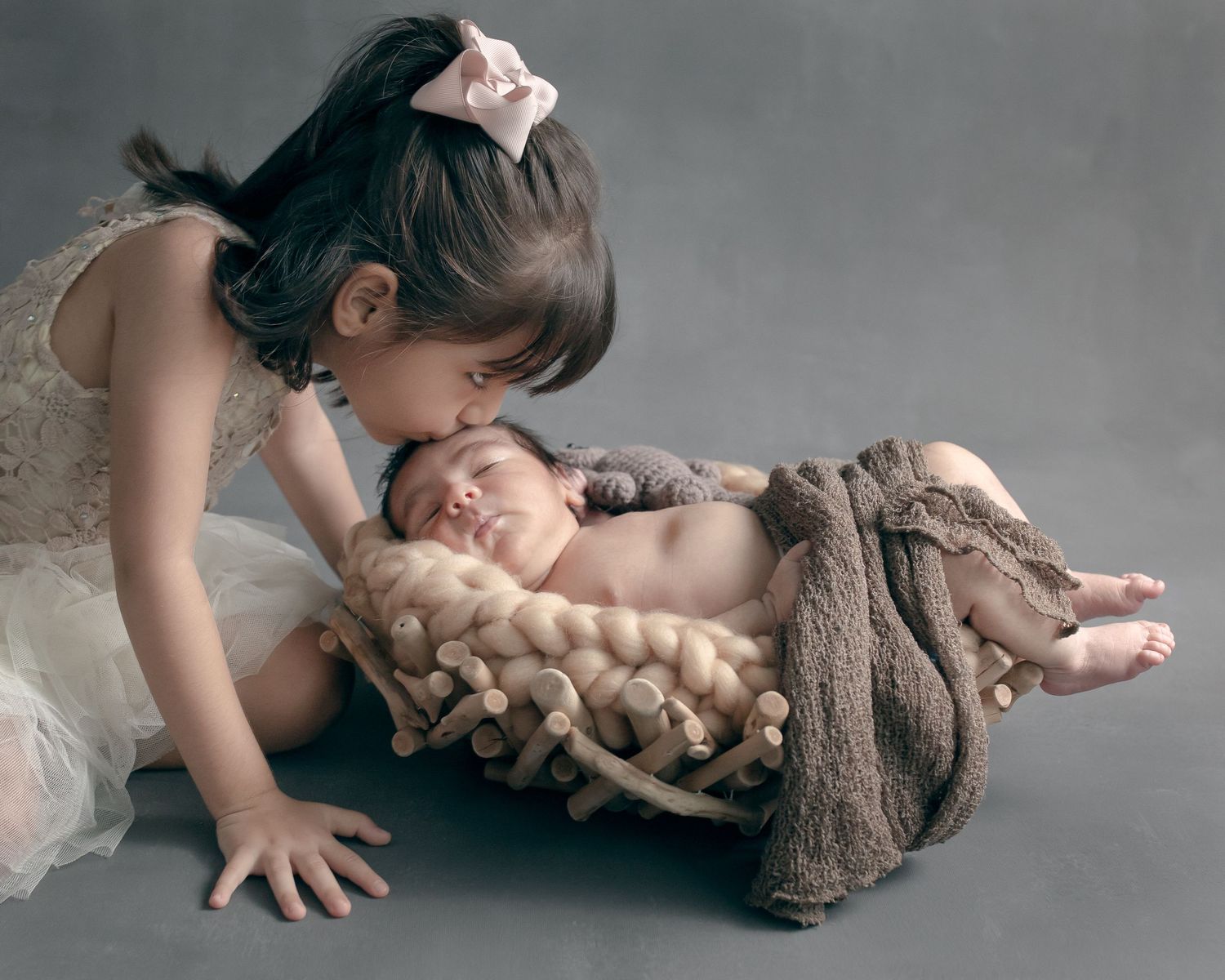 Tender scene of loving interaction with sleeping newborn on textured brown blanket.