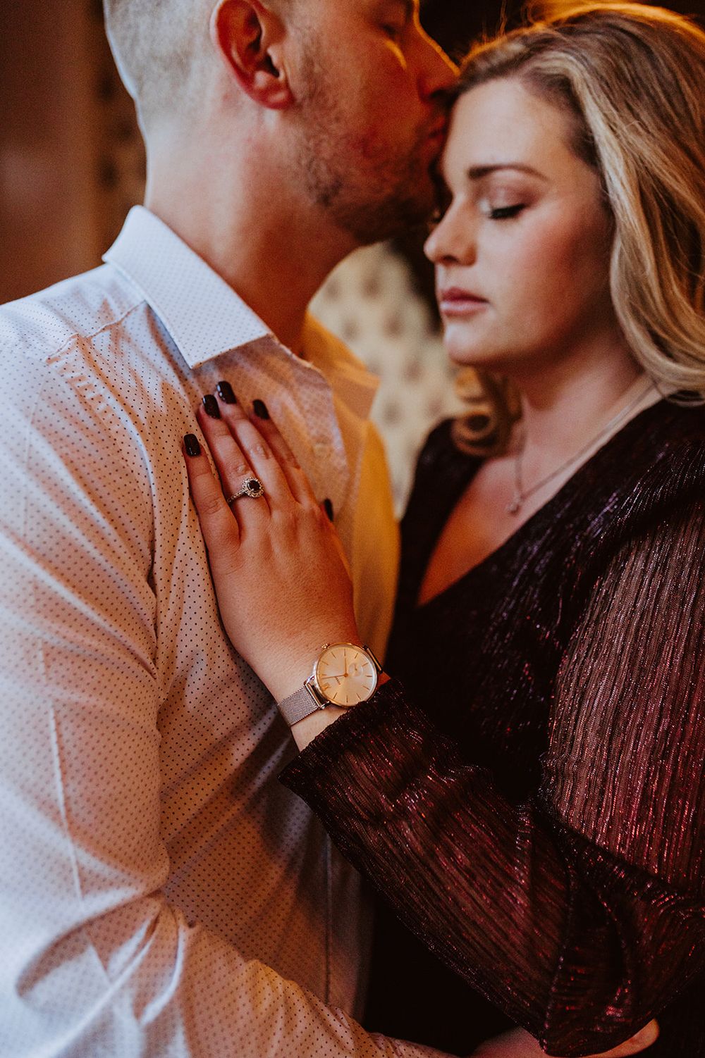 An intimate portrait of a couple embracing, with warm lighting and elegant formal attire.