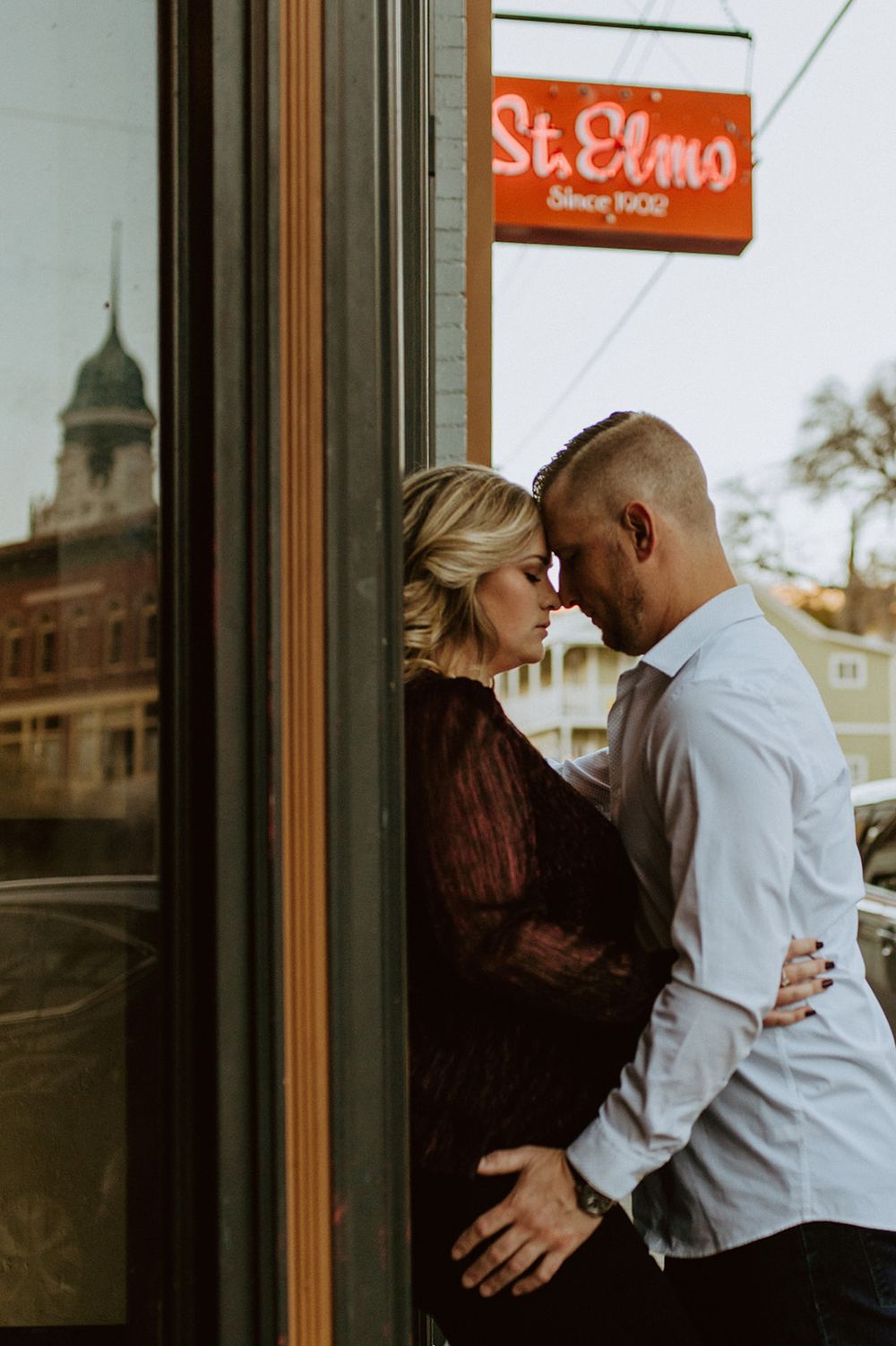 A couple shares a tender moment outside St. Elmo's storefront window.
