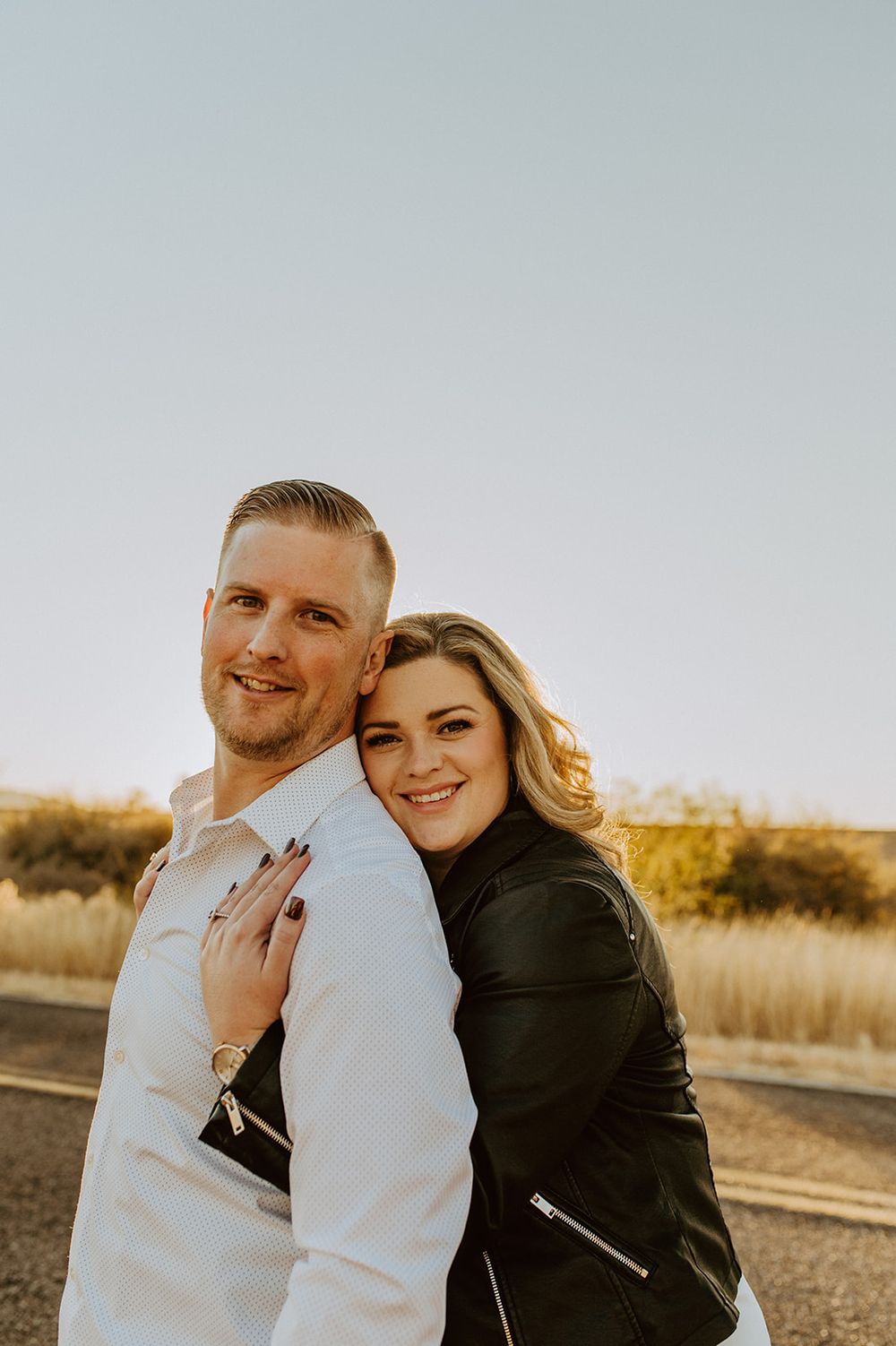 A couple poses together in golden sunlight during an outdoor photoshoot.