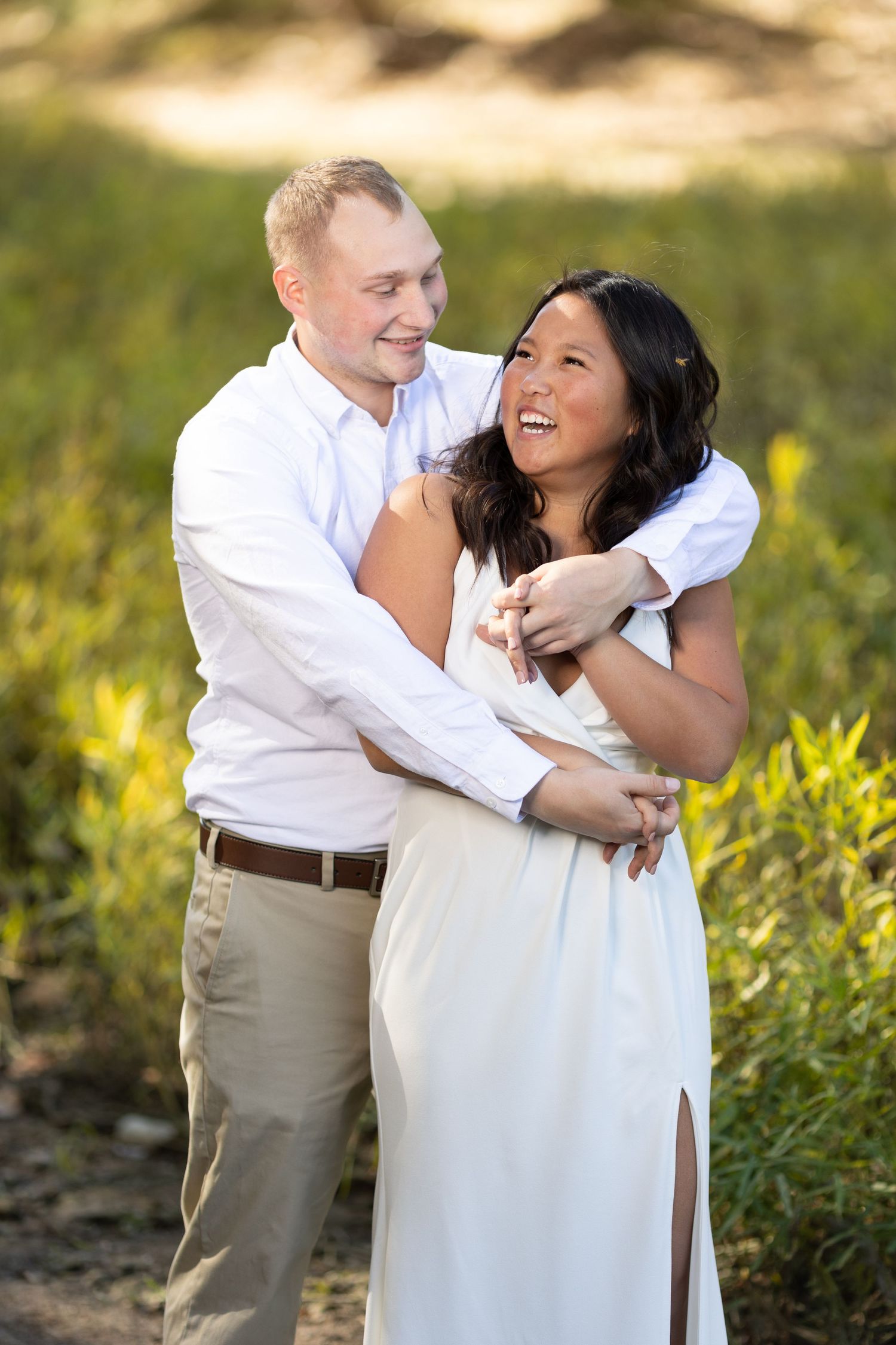 Newly engaged Illinois couple laugh together on the banks of a creek.