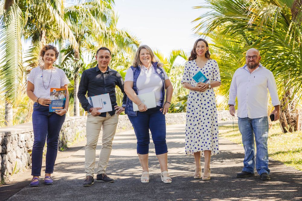 Group of people walking along a palm tree-lined path during an outdoor event.