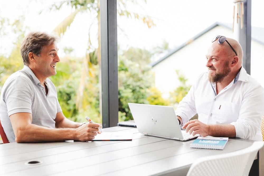 Business professionals working on laptops in a bright modern office space with windows.