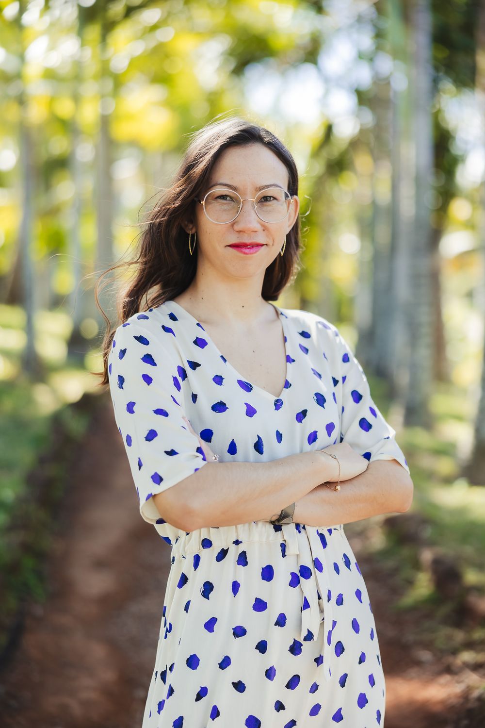 Person in polka dot dress posing outdoors with palm trees in background.