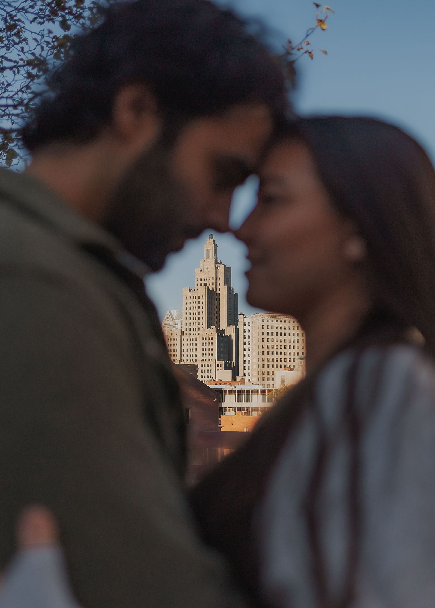 A romantic couple in silhouette frames a tall art deco building in Providence during golden hour.