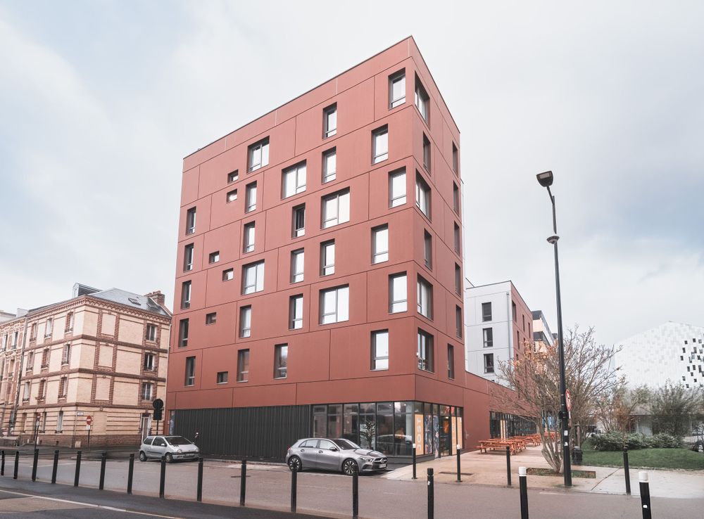 Modern residential building with distinctive terra cotta colored facade and geometric windows.