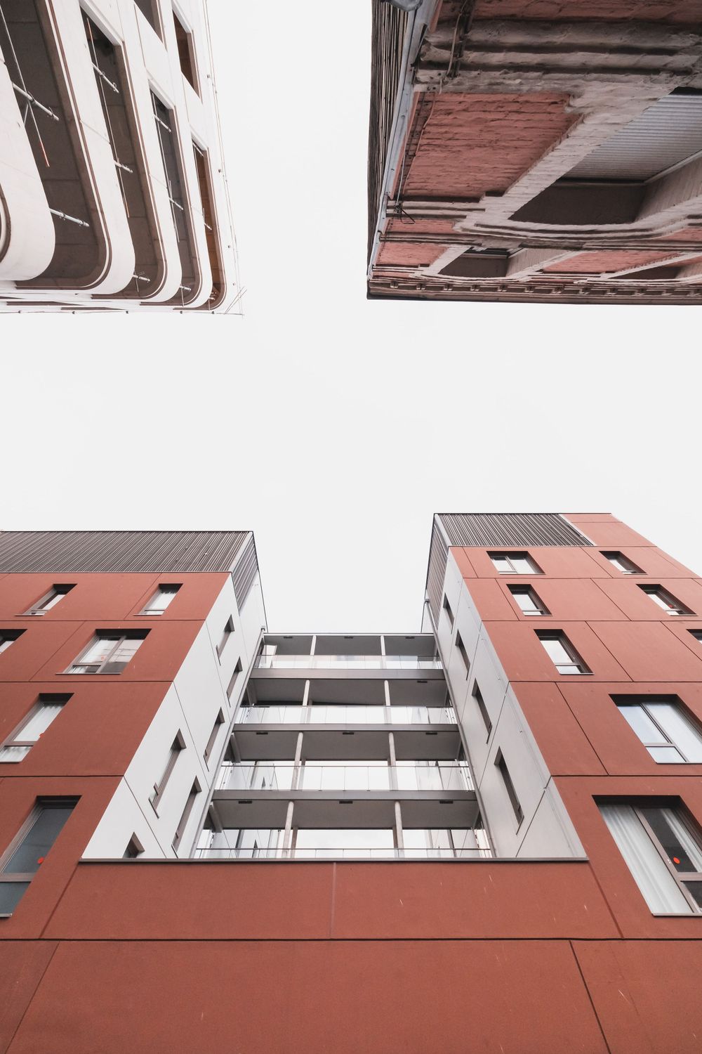 Looking up at modern residential buildings with terracotta facades forming geometric patterns.