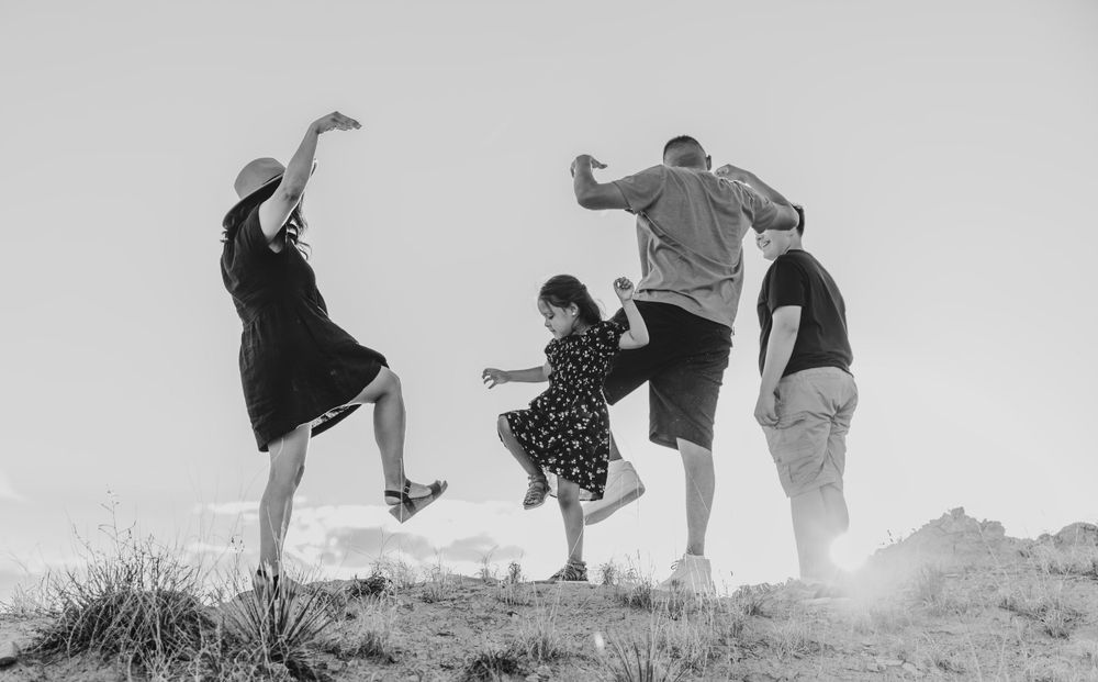 Black and white photo of people jumping joyfully on a hill.