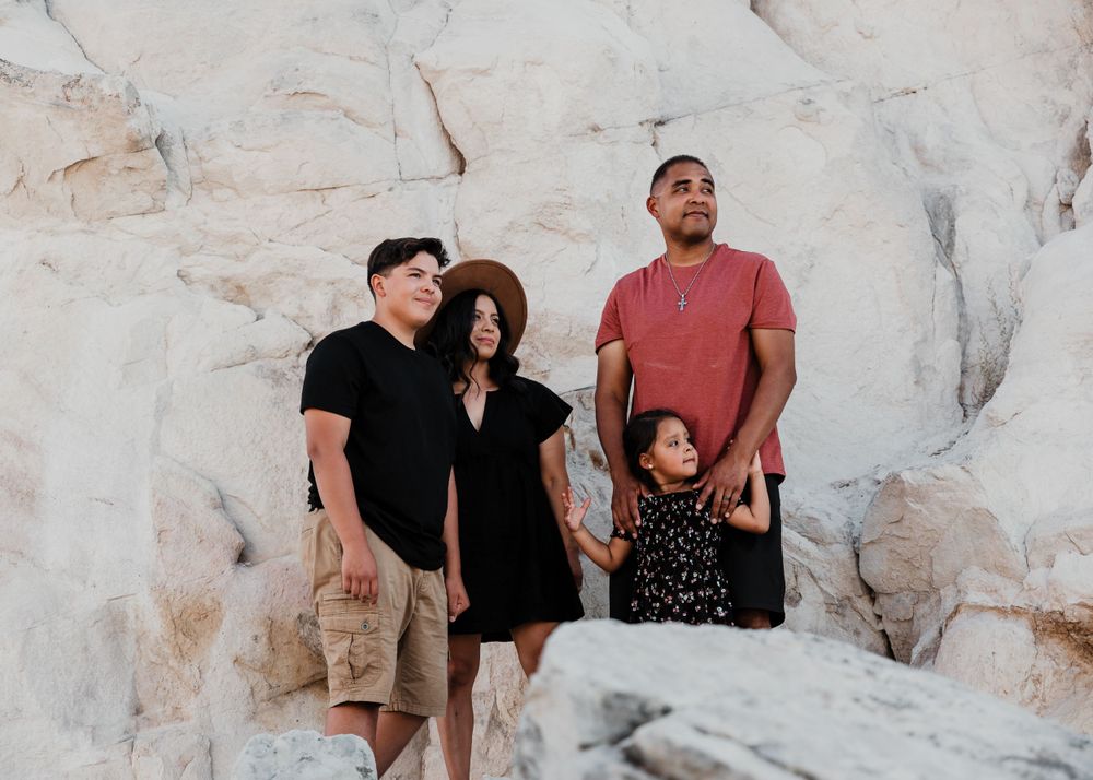Family posing together against white rock formation in desert setting.