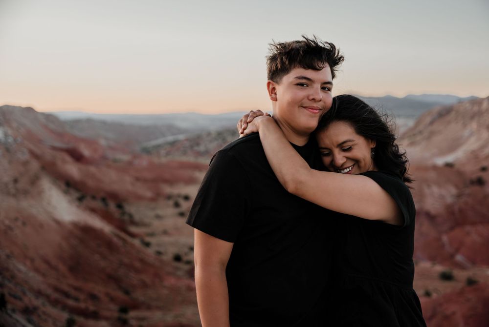 A couple embraces against backdrop of red rock canyons at sunset.