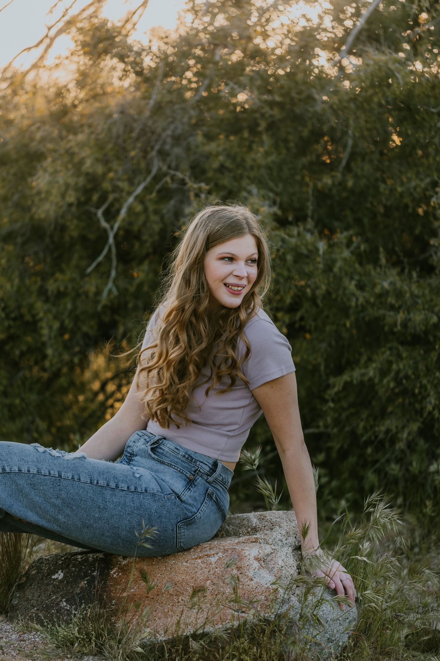 Person in casual attire lounging on a rock formation during sunset.