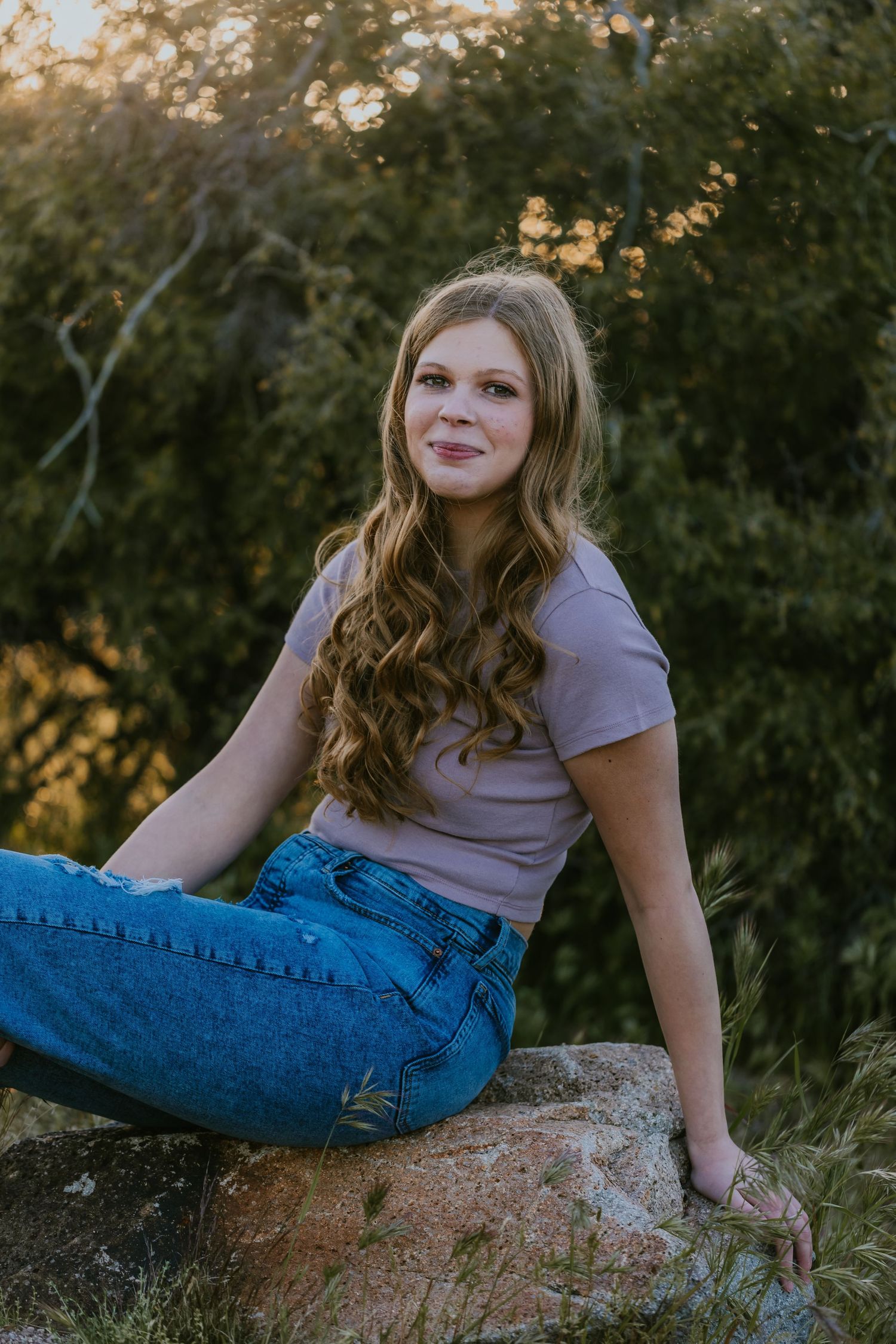 Casual outdoor portrait session on natural rock formation during golden hour.