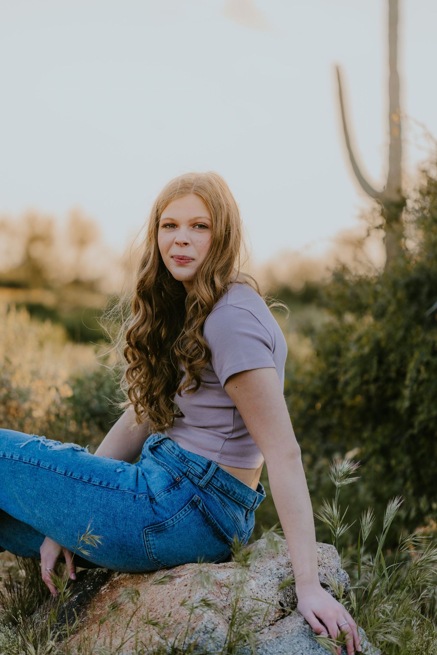Casual outdoor portrait with person lounging on rocky ground at sunset.