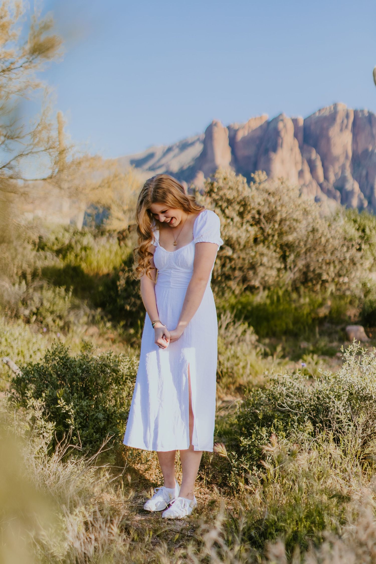 Desert photoshoot featuring white dress and natural desert vegetation against mountain backdrop.