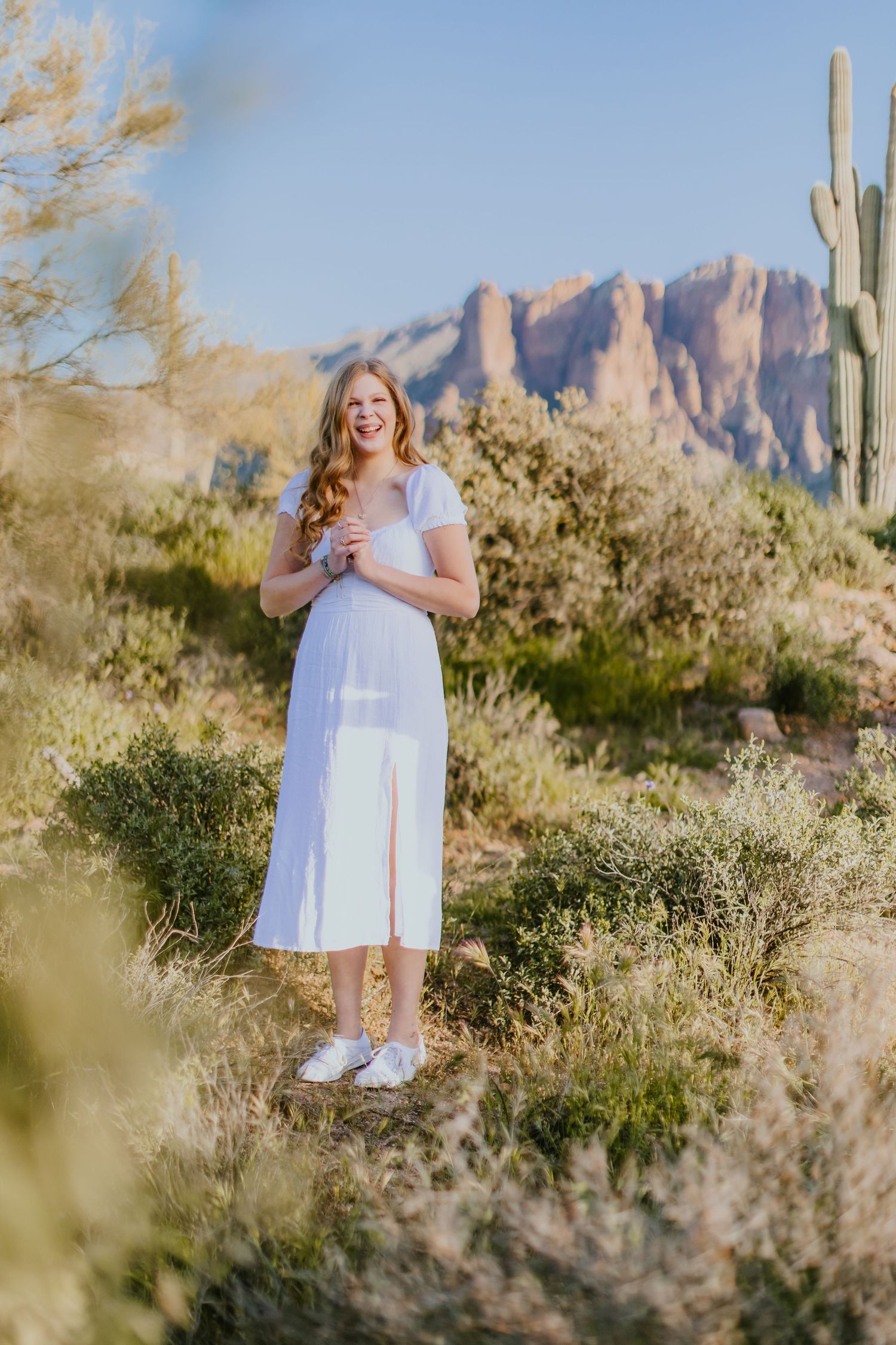 Desert photography session with mountains and native plants creating a natural frame.
