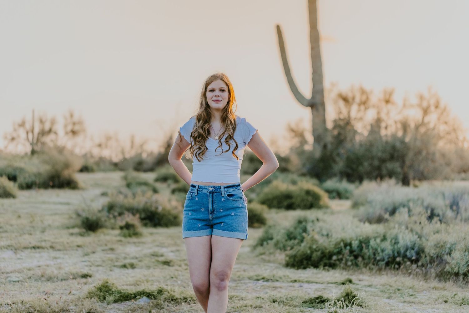 Person posing in casual wear against desert backdrop during sunset photography session.