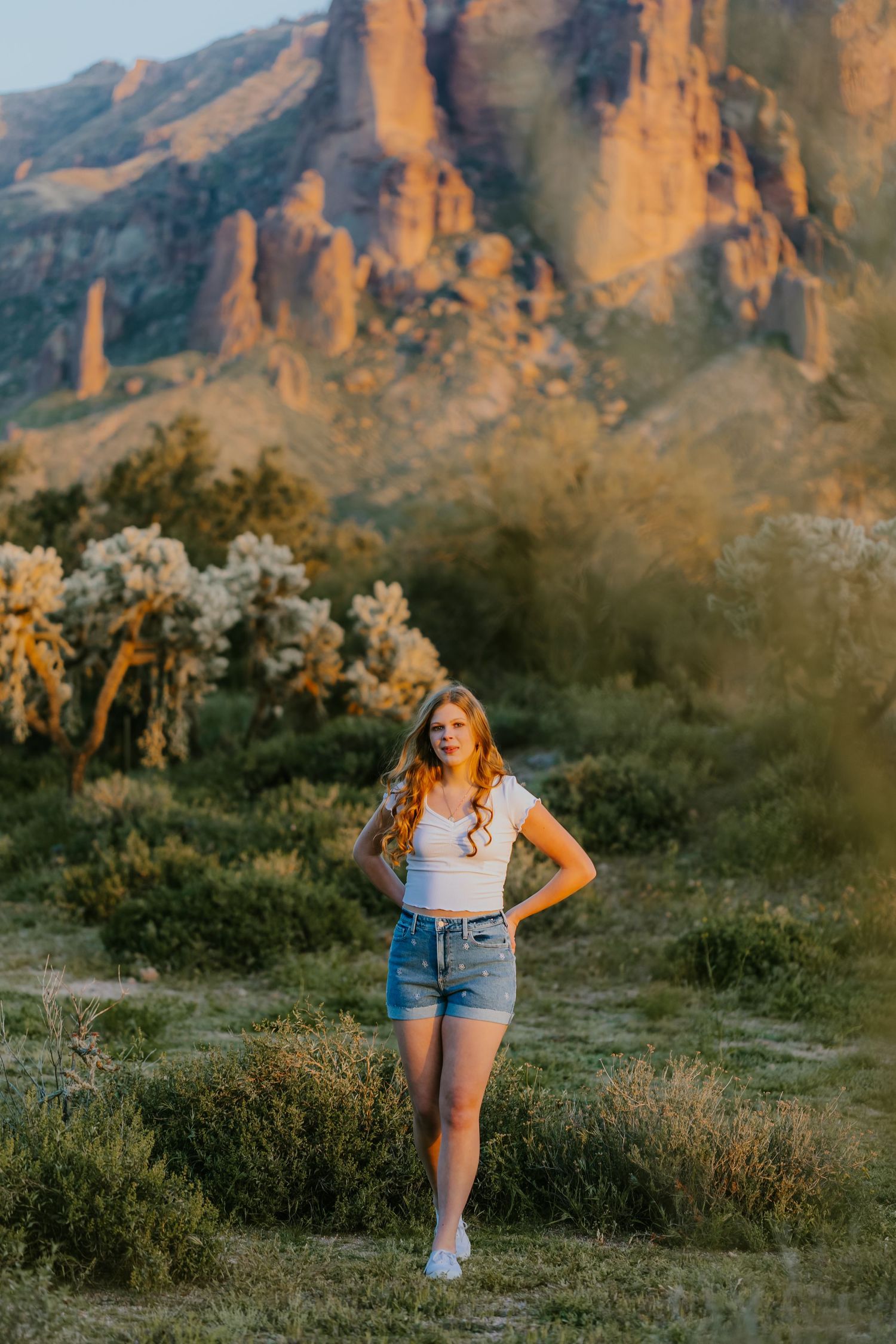 Outdoor portrait session in desert terrain with mountainous backdrop at golden hour.