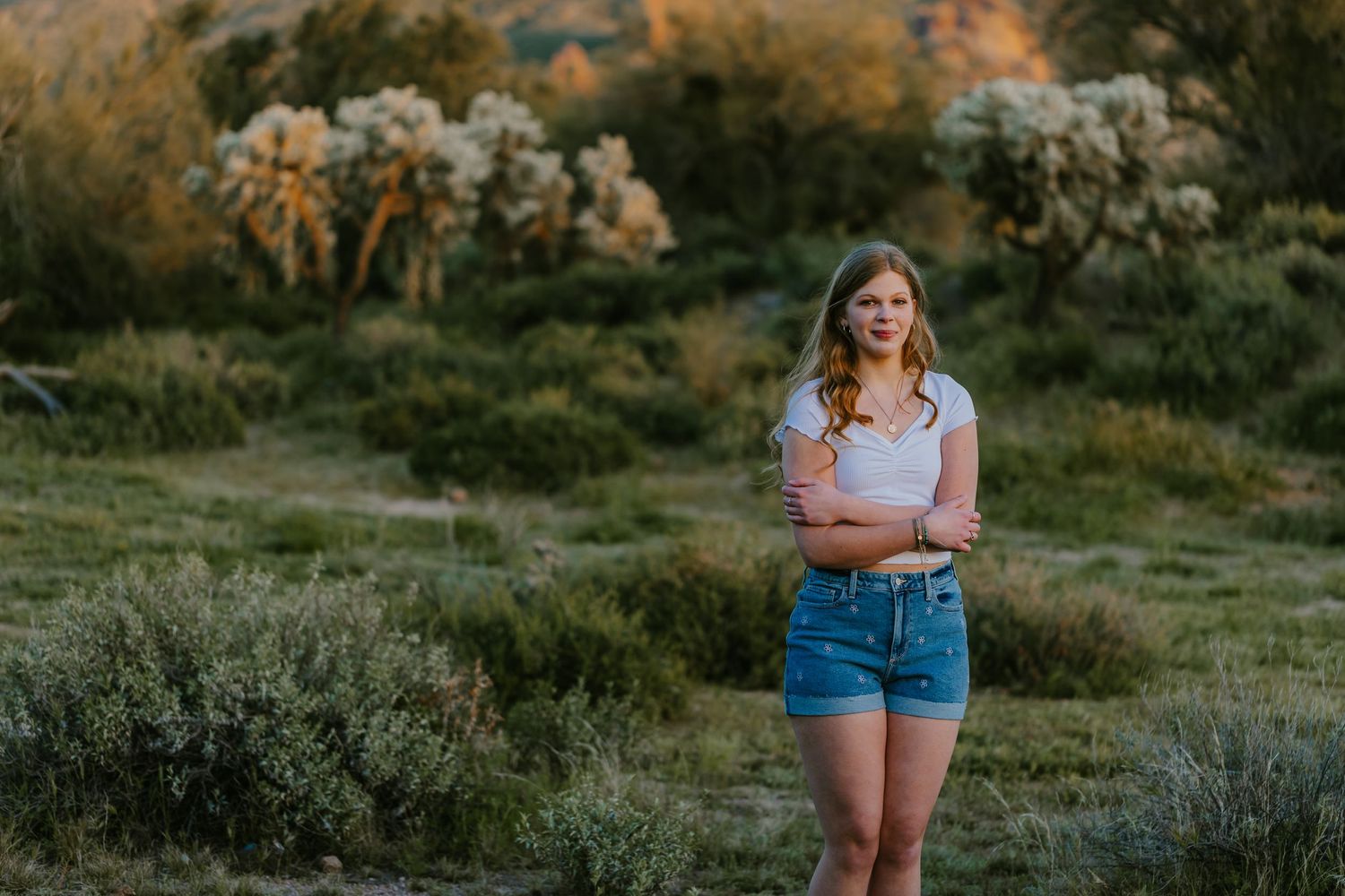 Desert photoshoot featuring casual summer attire with mountains and desert flora in background.