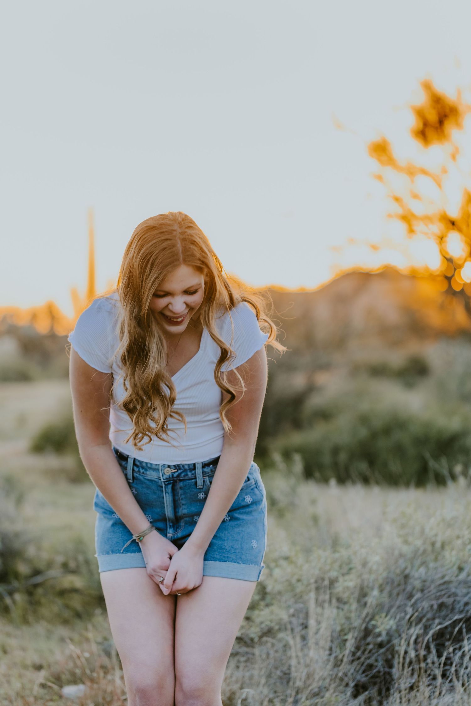 Playful outdoor portrait in casual summer wear against desert landscape at sunset.