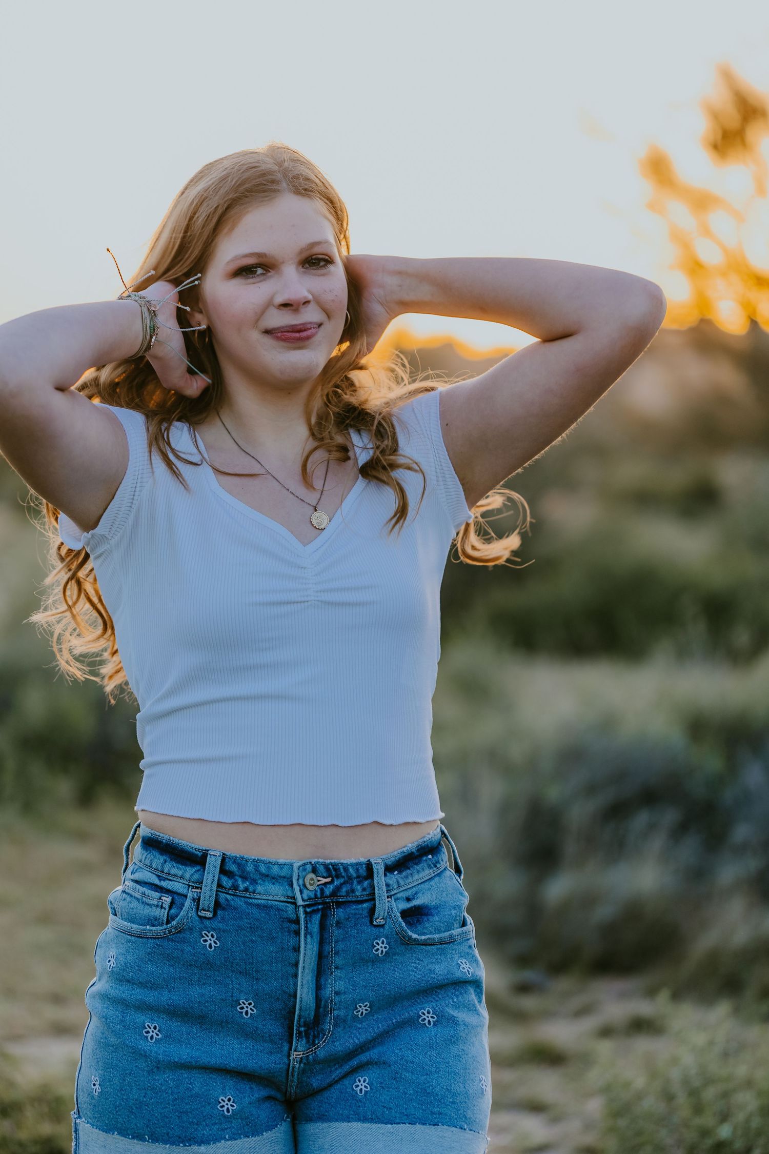 Candid outdoor portrait with person in white top and denim shorts during sunset.