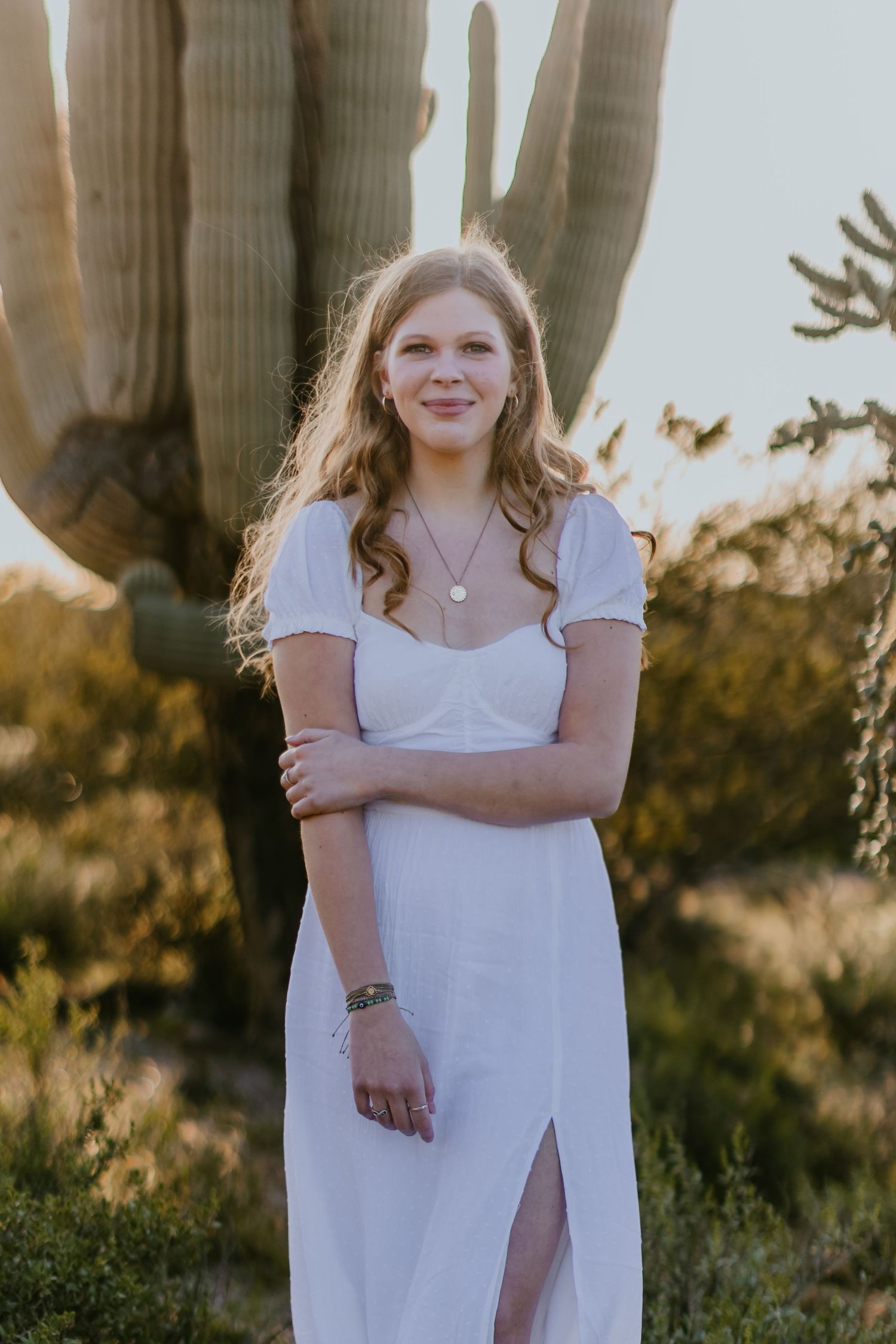 A white dress photoshoot in front of a saguaro cactus during golden hour in the desert.