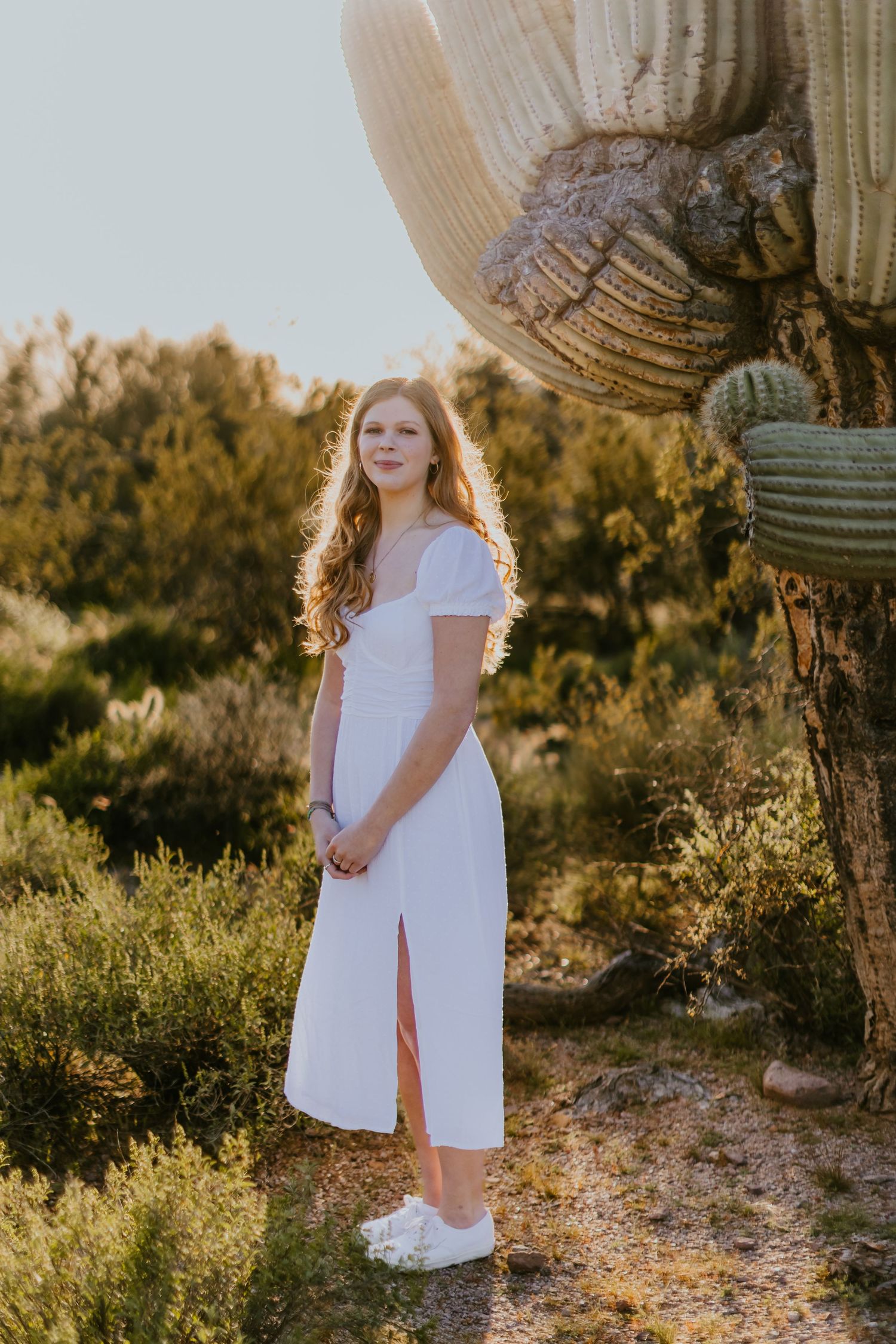 Outdoor desert photography featuring white dress and towering saguaro cactus.