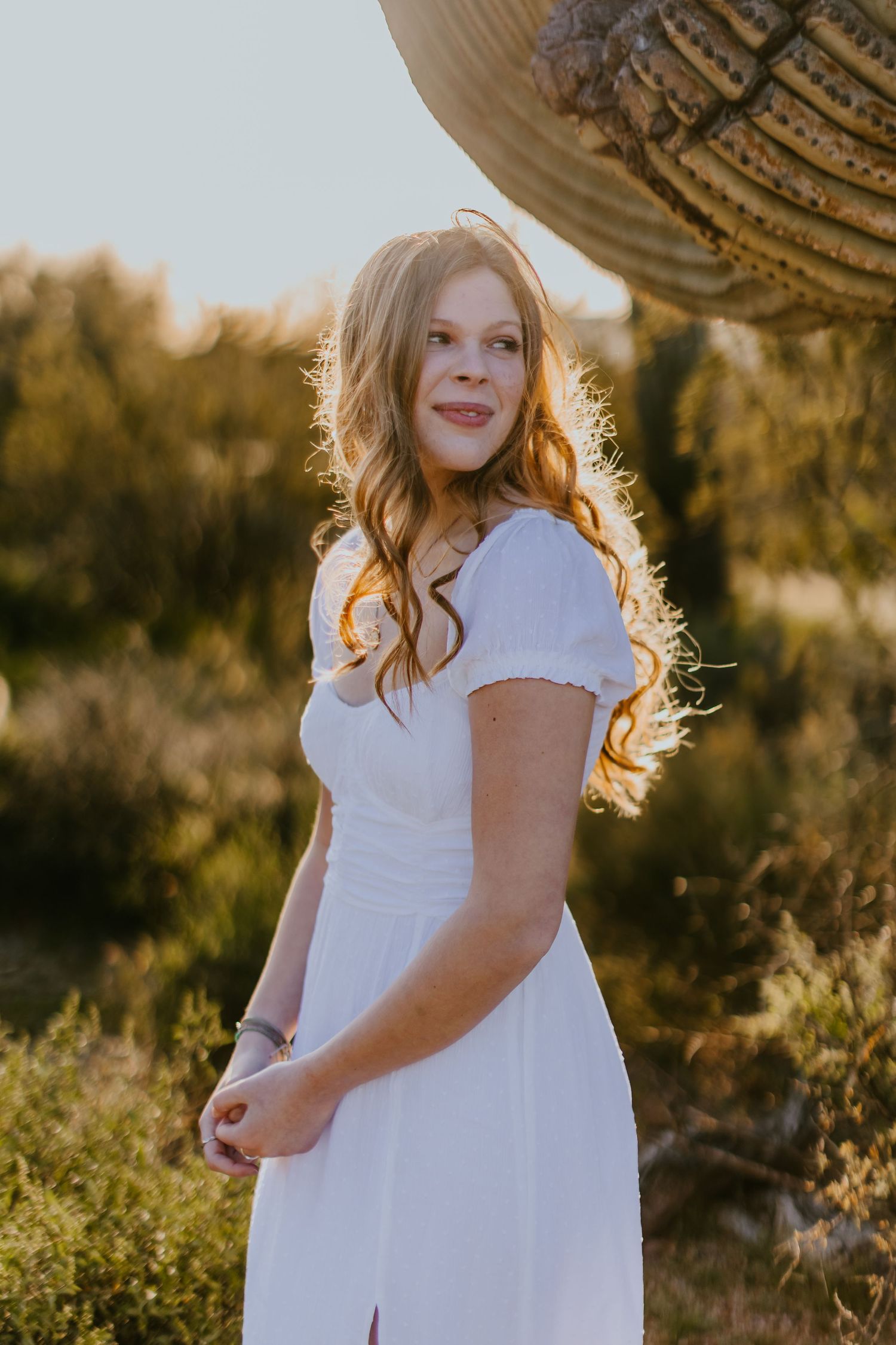 Sunset portrait session in white dress with desert flora backdrop.