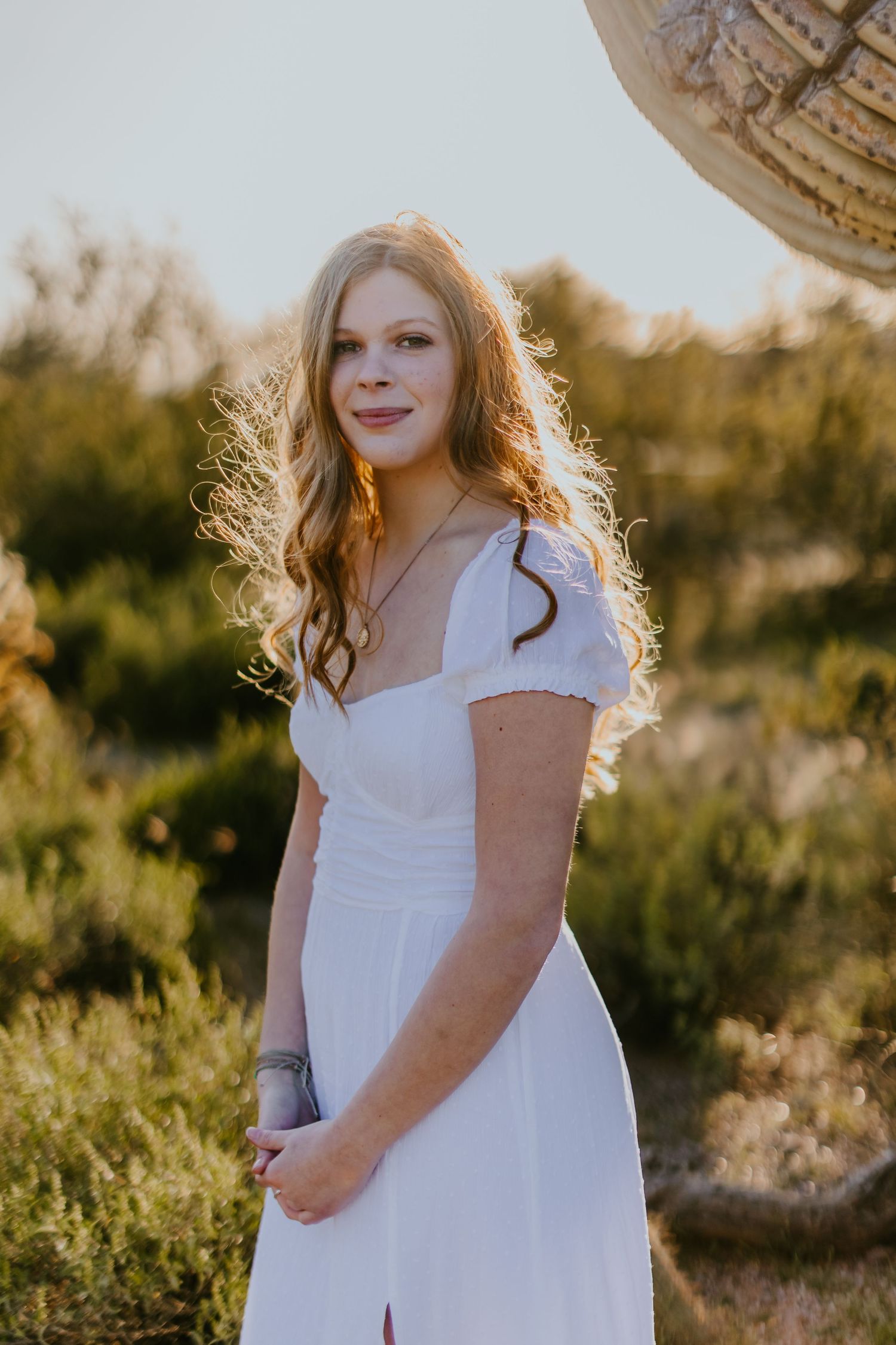 Elegant white dress portrait against a natural desert landscape at sunset.