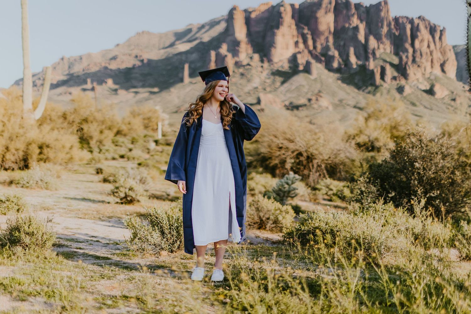 Graduation portrait with saguaro cactus and mountain vista in Arizona desert.