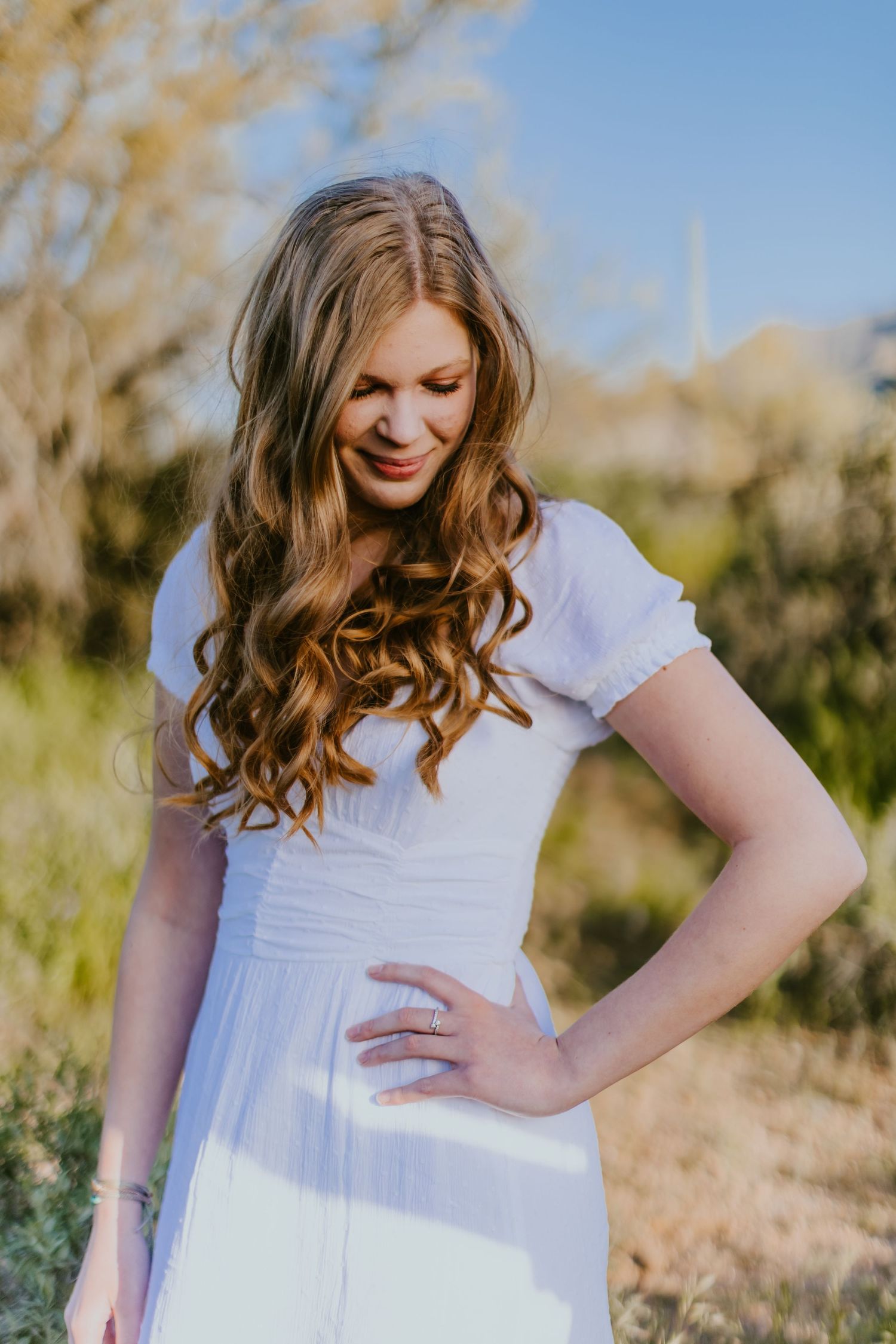 Candid desert photoshoot featuring a white dress and natural desert scenery.