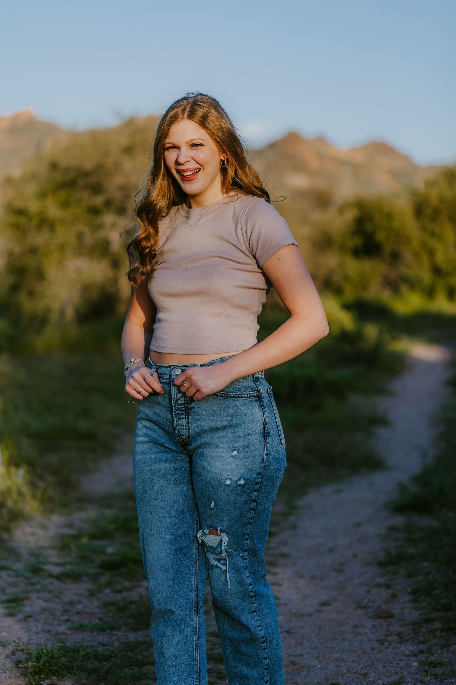 Casual lifestyle portrait on a desert trail with mountains in the background.