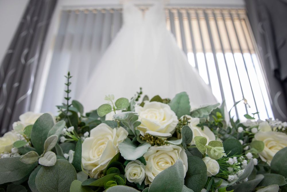 Bride and bridesmaids bouquet, with wedding dress hung up in background.