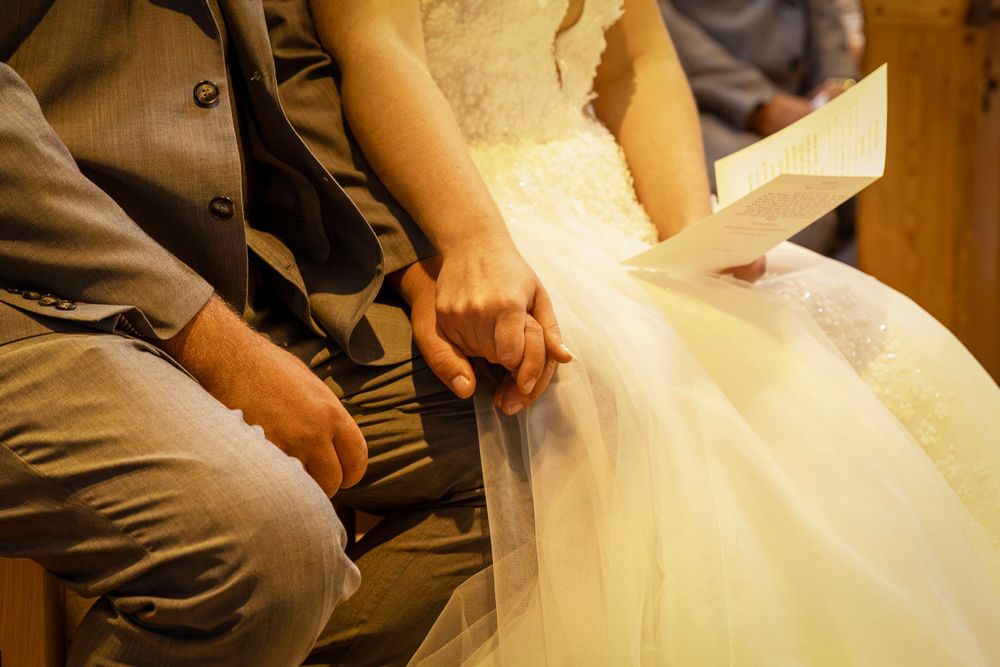 Couple close up shot of holding hands during church ceremony