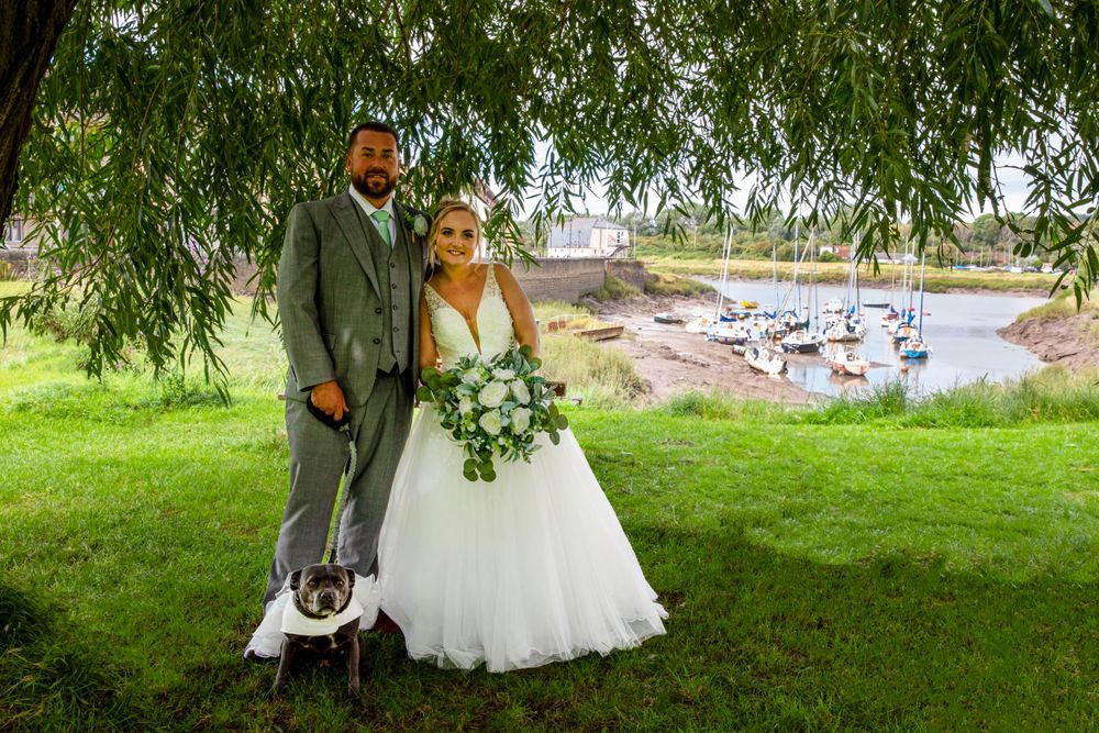 Bride groom and pet dog by river creek.