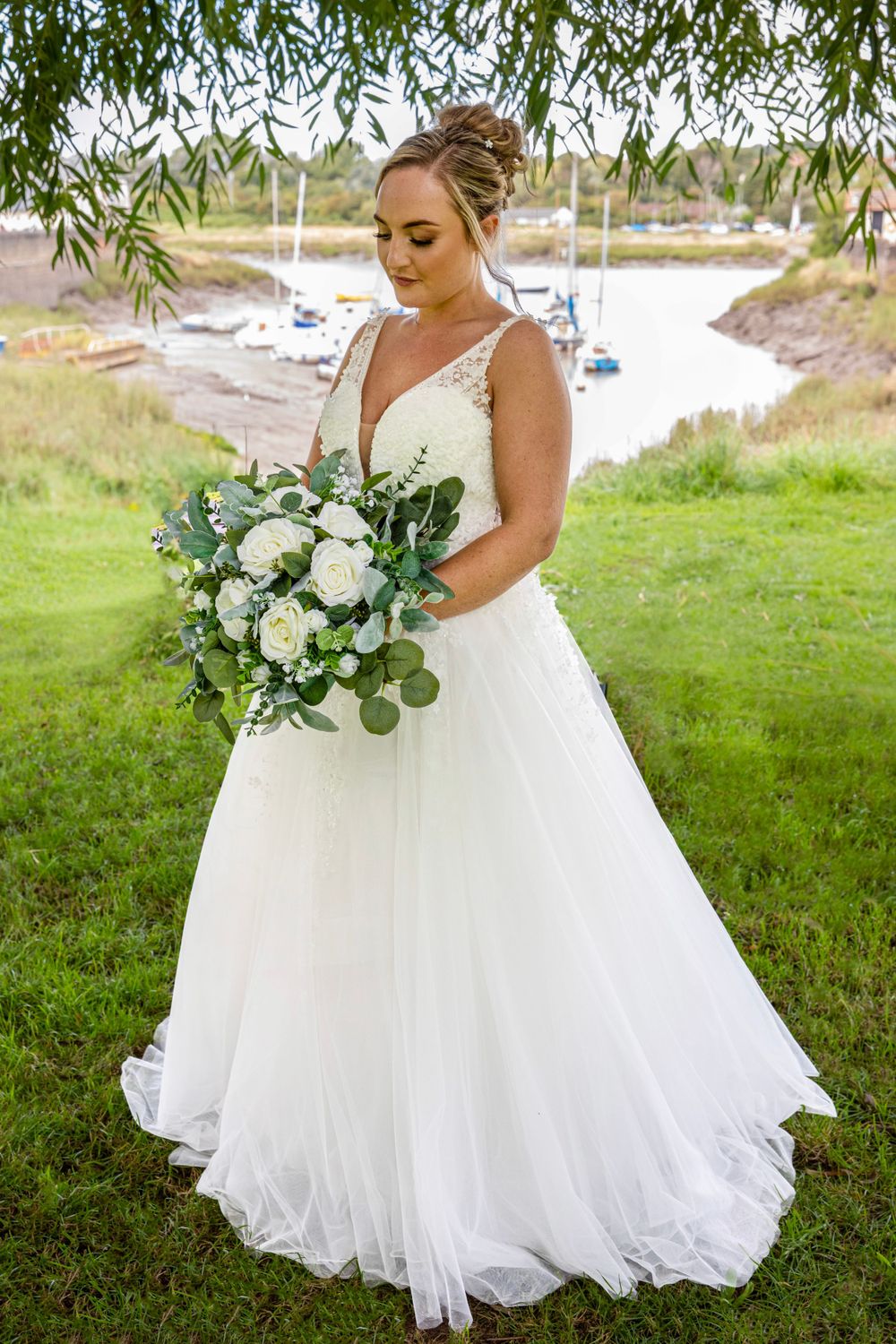 Beautiful bride by river creek. Full length shot, bride looking at flowers.