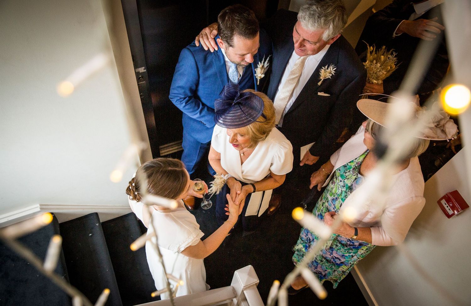 Wedding guests celebrate and dance together at an indoor reception venue with warm lighting.
