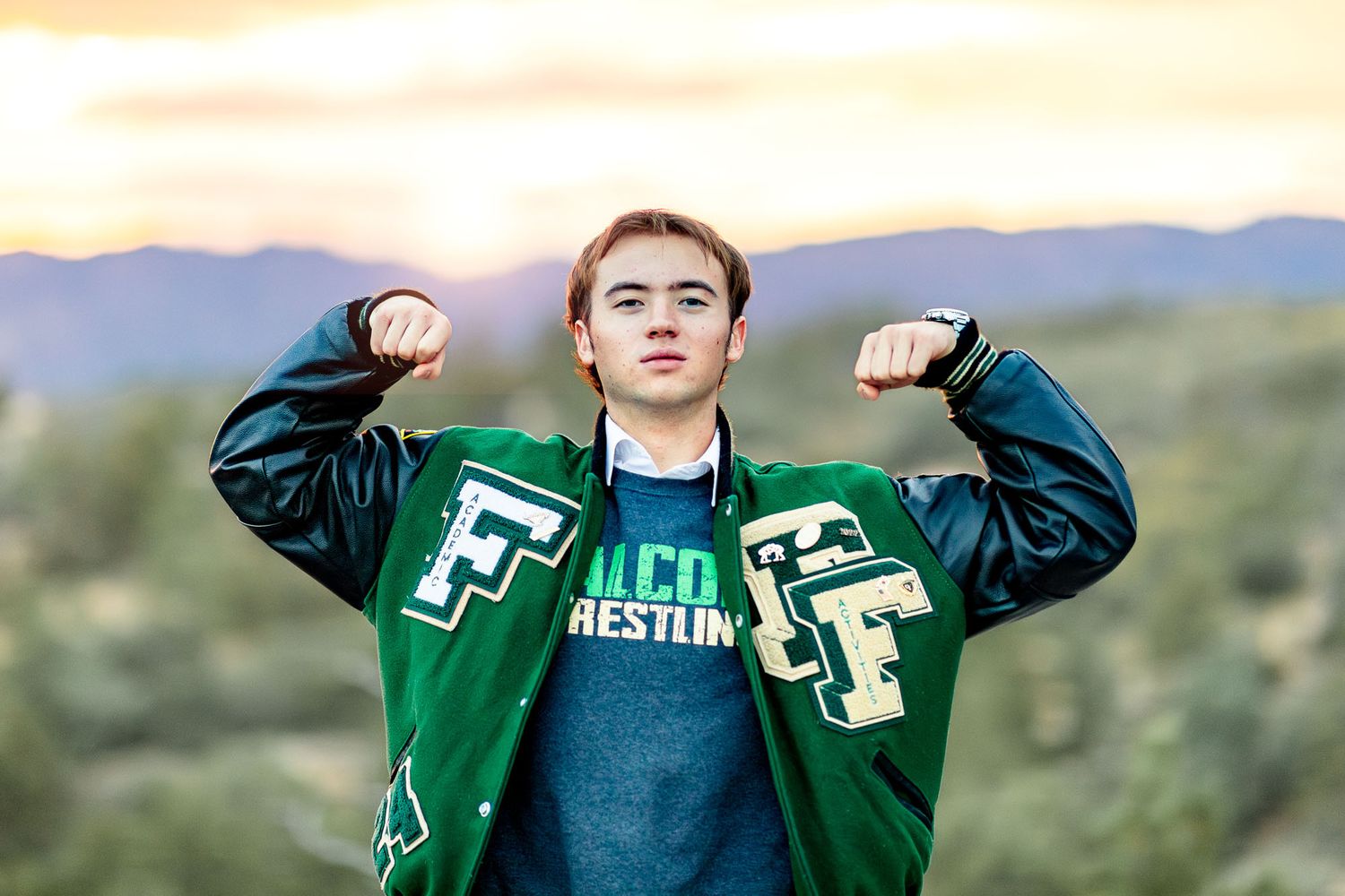 Senior guy poses at sunset with flexed arms at his senior session at Palmer Park in Colorado Springs.