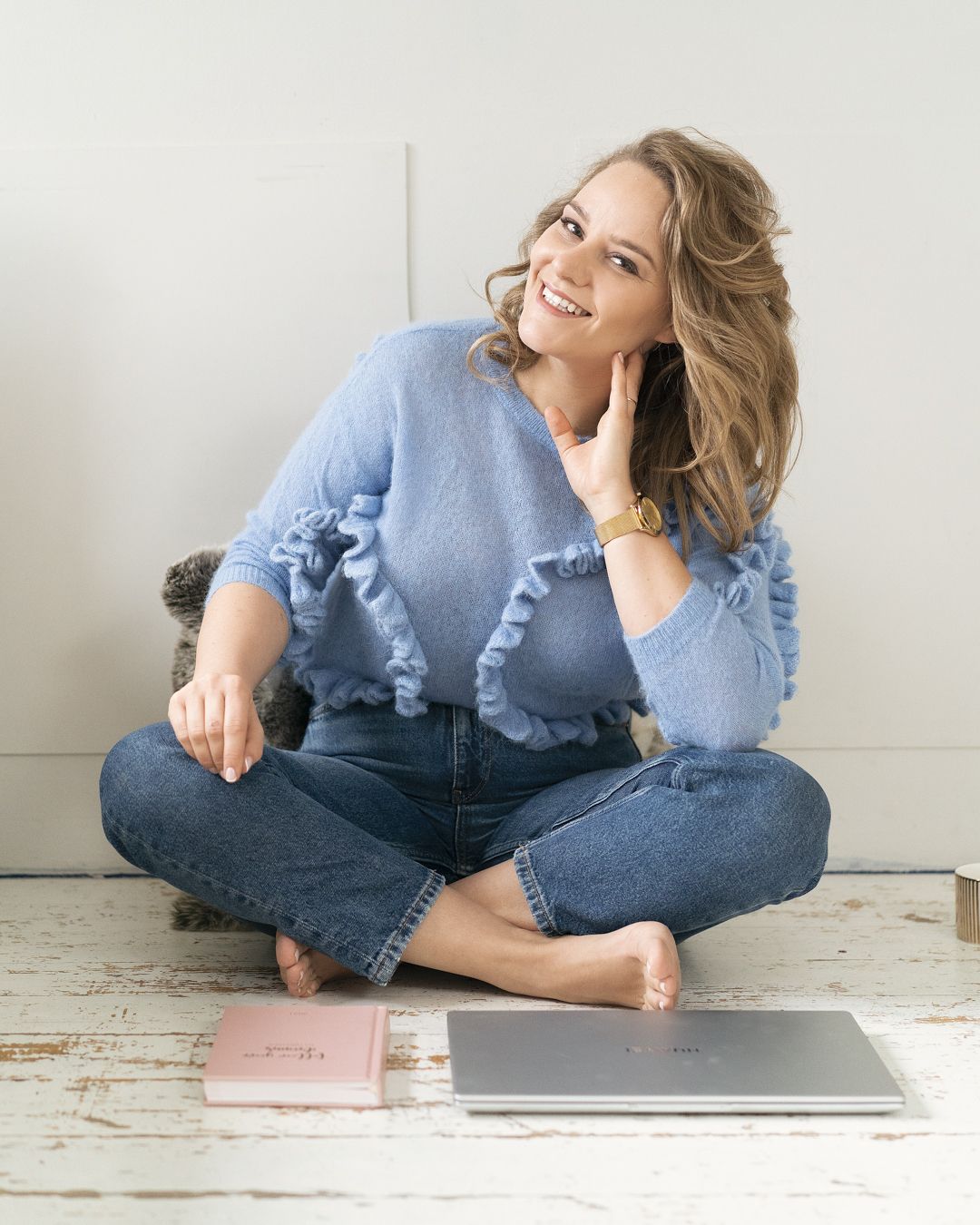 Casual lifestyle photo showing relaxed pose with laptop on wooden floor.