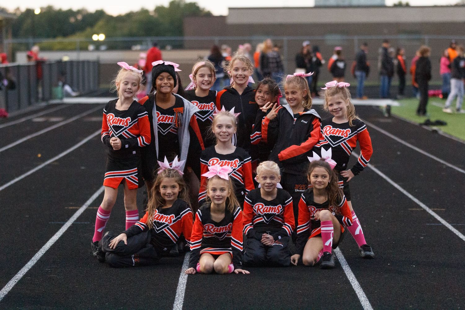 Youth cheerleading squad poses together on track field in red and black uniforms.youngstown photographer boardman photographer ohio photogra