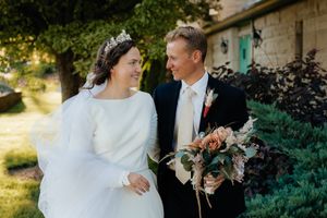 A couple shares a romantic moment in a garden setting with lush greenery and natural lighting.