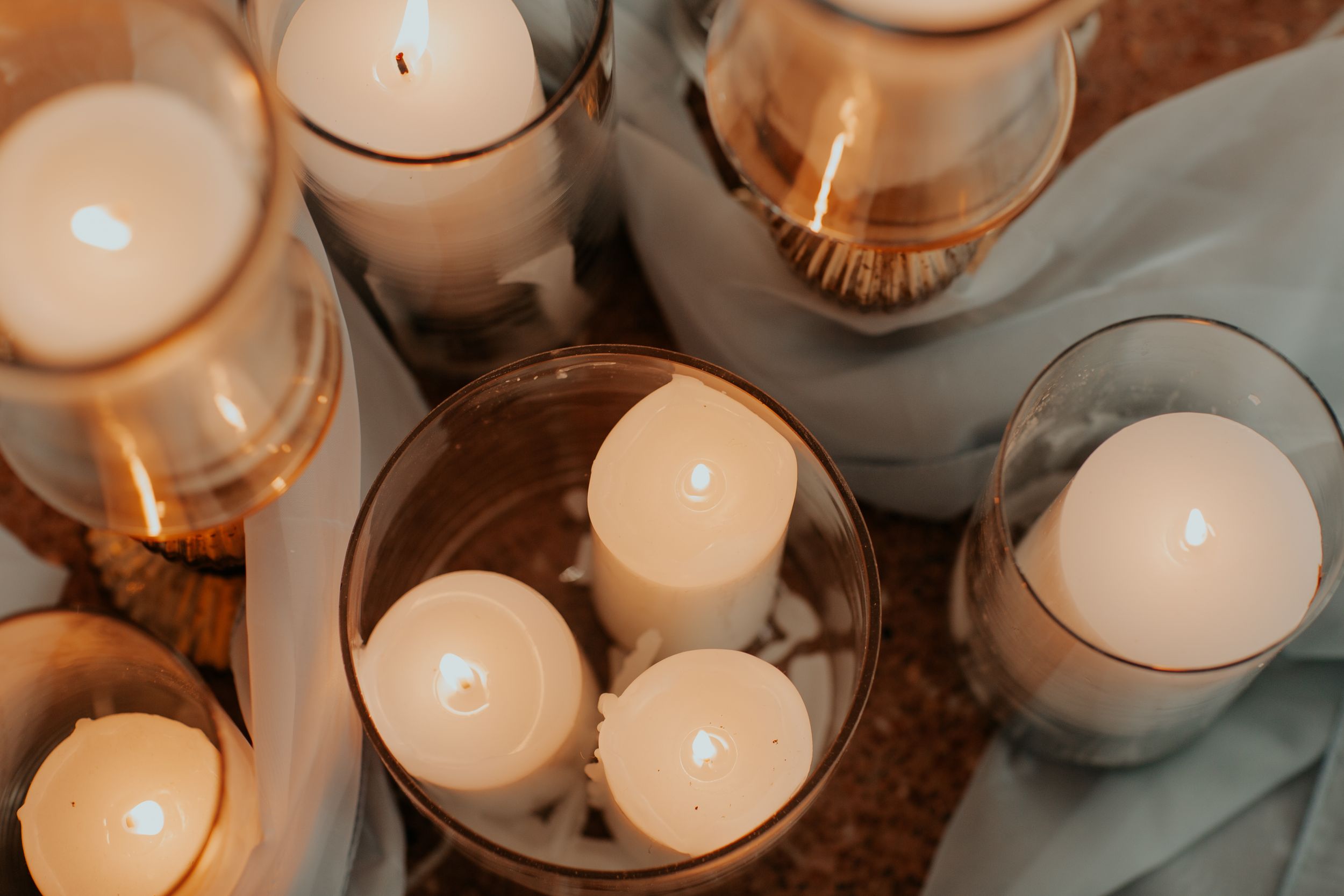 Glowing white candles in glass holders create an intimate atmosphere for a wedding reception.