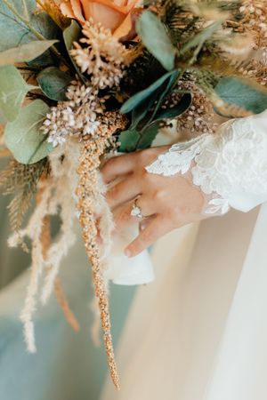 Delicate floral bouquet with eucalyptus and peach blooms against white lace details.